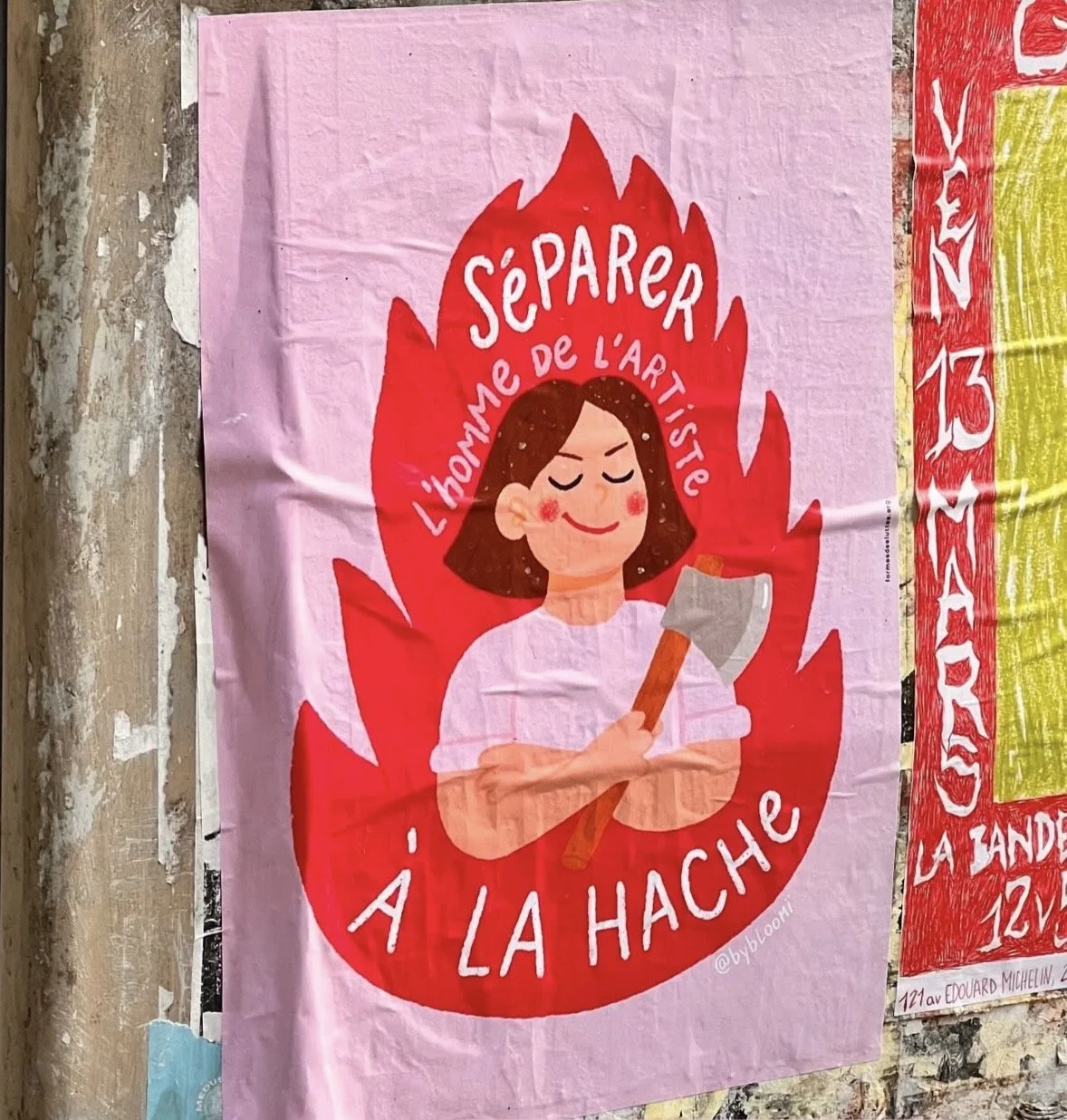 Affiche avec une illustration d'une femme souriante portant un t-shirt blanc, tenant une hache, entourée de flammes rouges. Texte en français : "Separer l'homme de l'artiste à la hache" sur un fond rose.