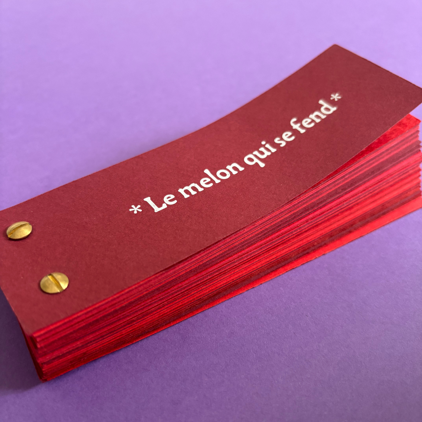Paquet de cartes rouges avec l'inscription "Le melon qui s'end*" en blanc, posé sur un fond violet.