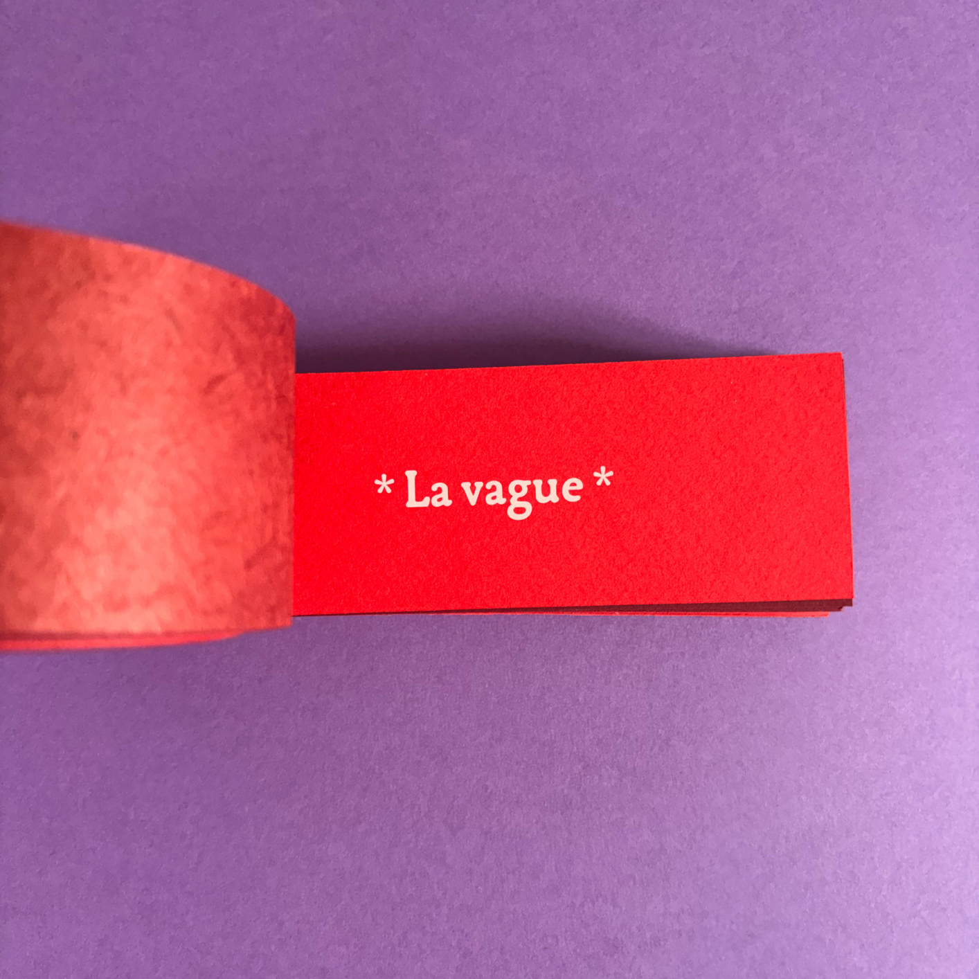 Une bande rouge avec l'inscription '*La vague*' sur un fond violet