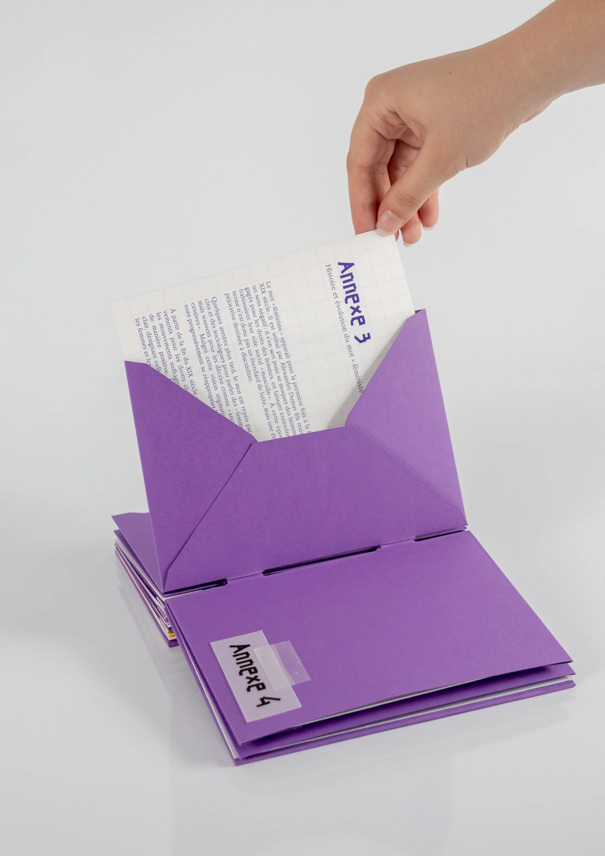 Une main sortant une fiche d'une enveloppe violette sur fond blanc.