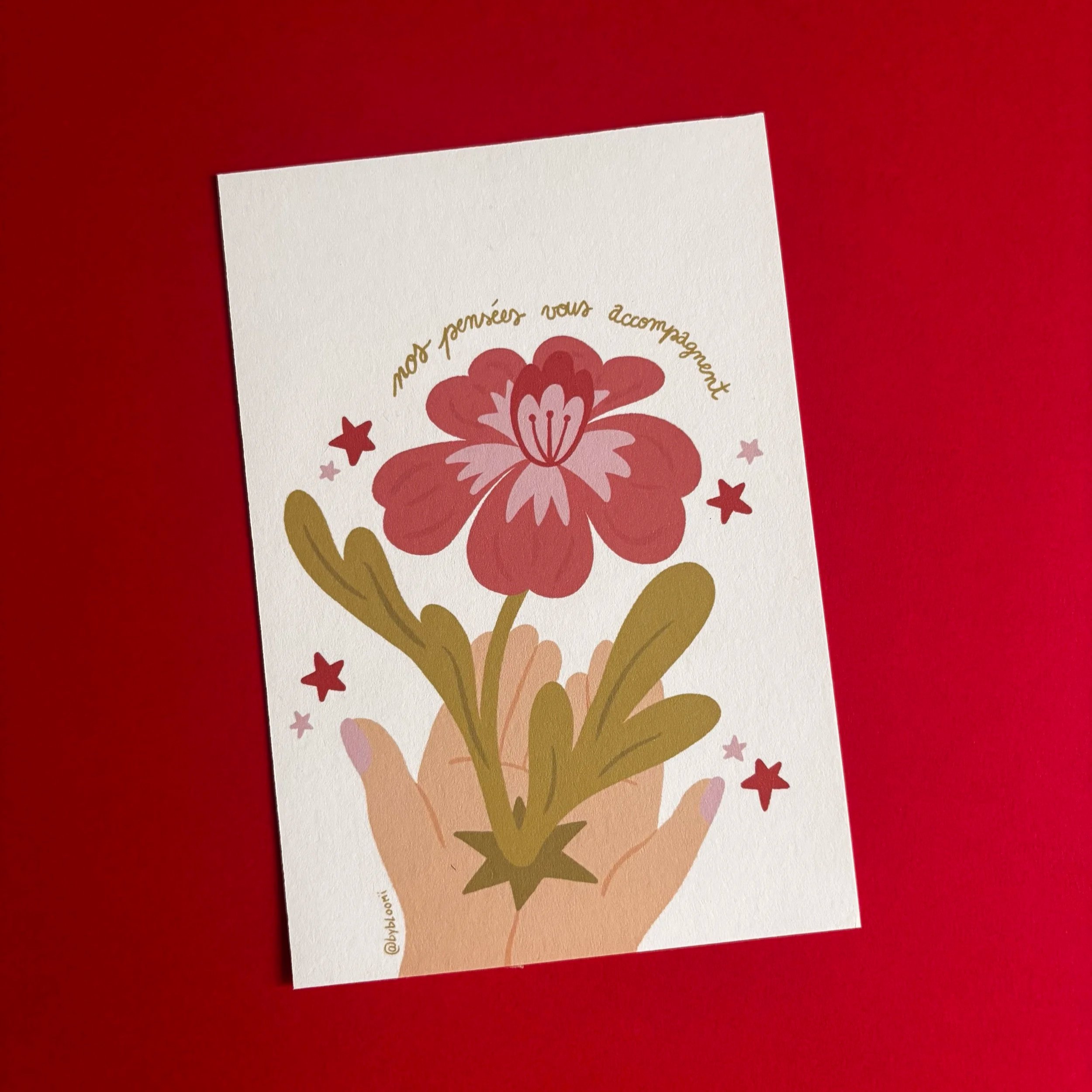Carte de vœux avec une illustration de fleurs roses et des étoiles, sur fond rouge.