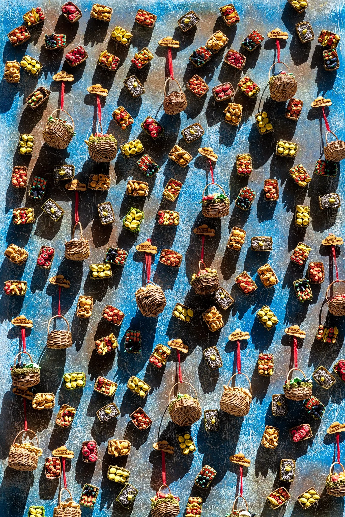 Small colorful baskets and objects arranged across a surface, casting distinct shadows in the sunlight.