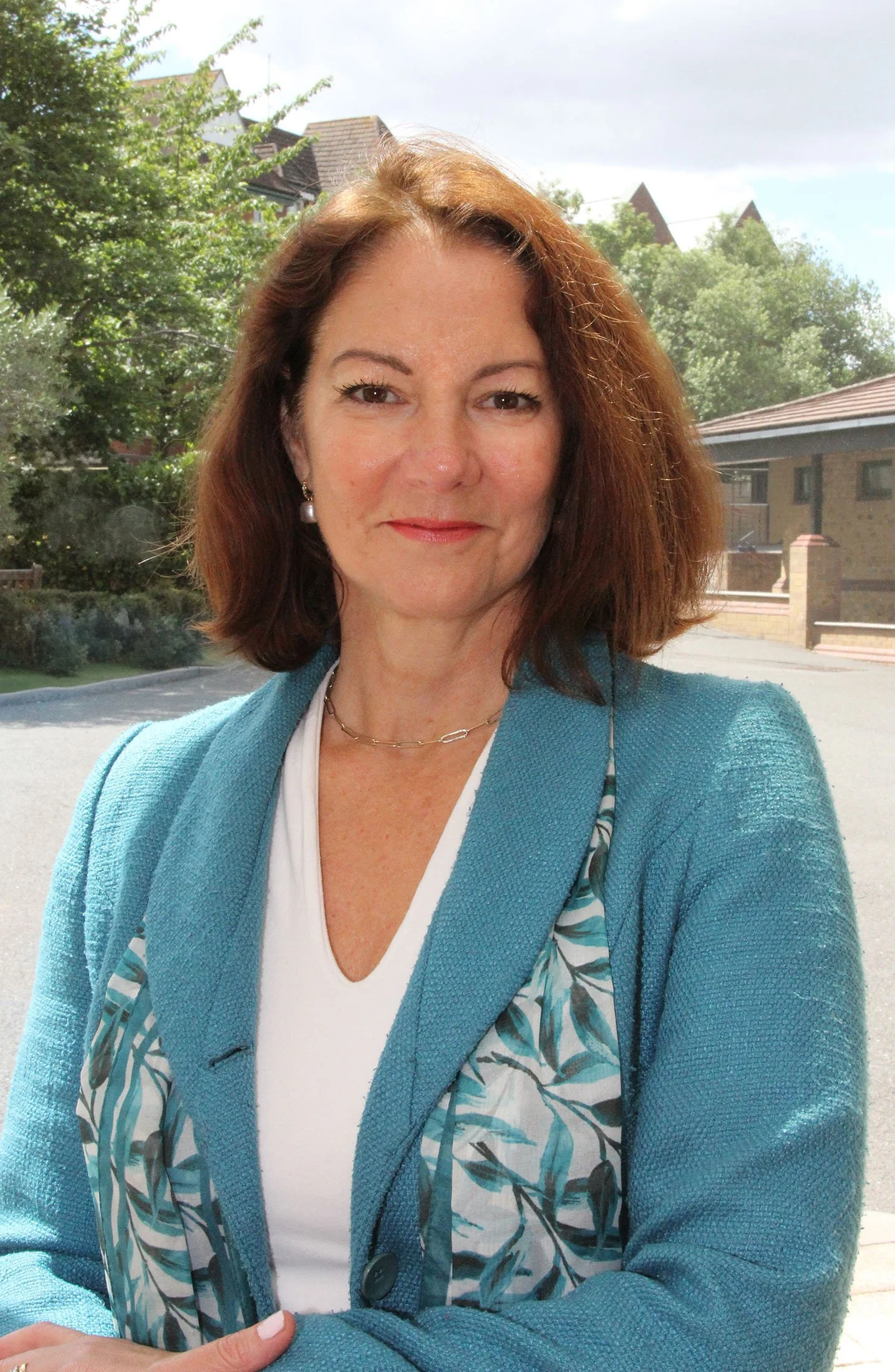 Fiona Allen-Pusey has shoulder-length auburn hair and wears a scarf with a leaf motif