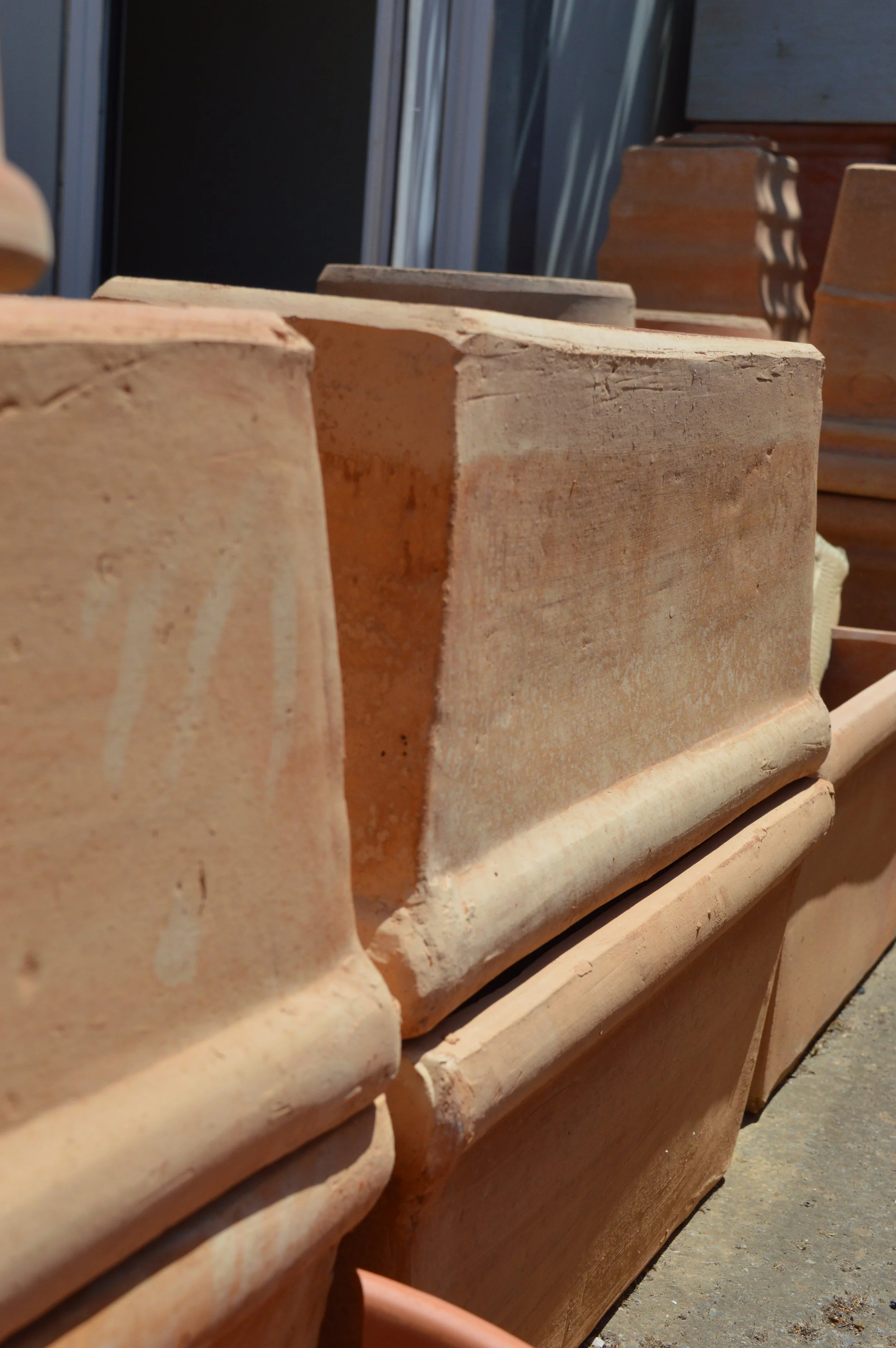 Close-up of beige clay chimney bricks stacked outdoors in sunlight.