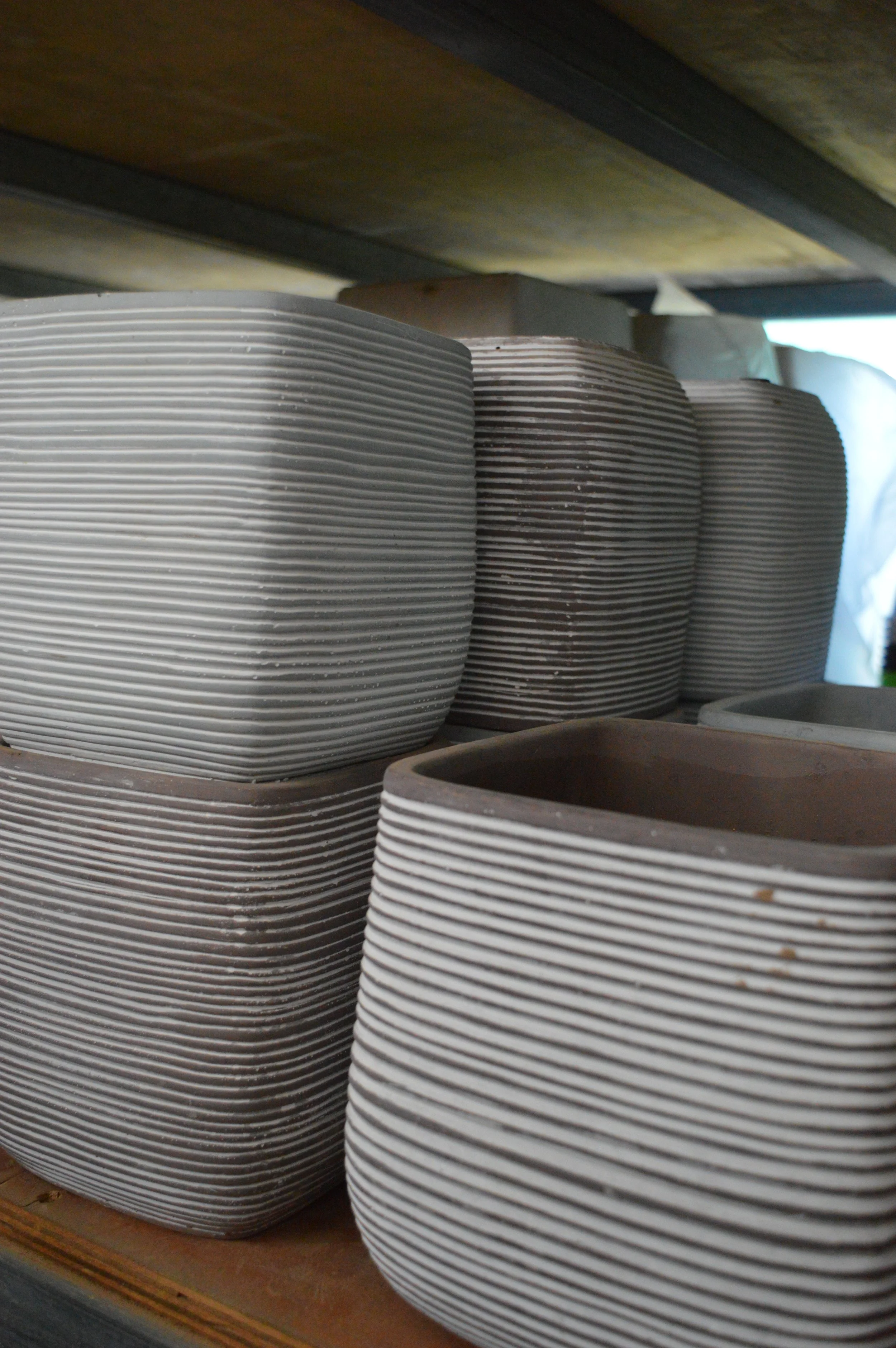 Stacked ceramic bowls with a ridged design on a wooden shelf.