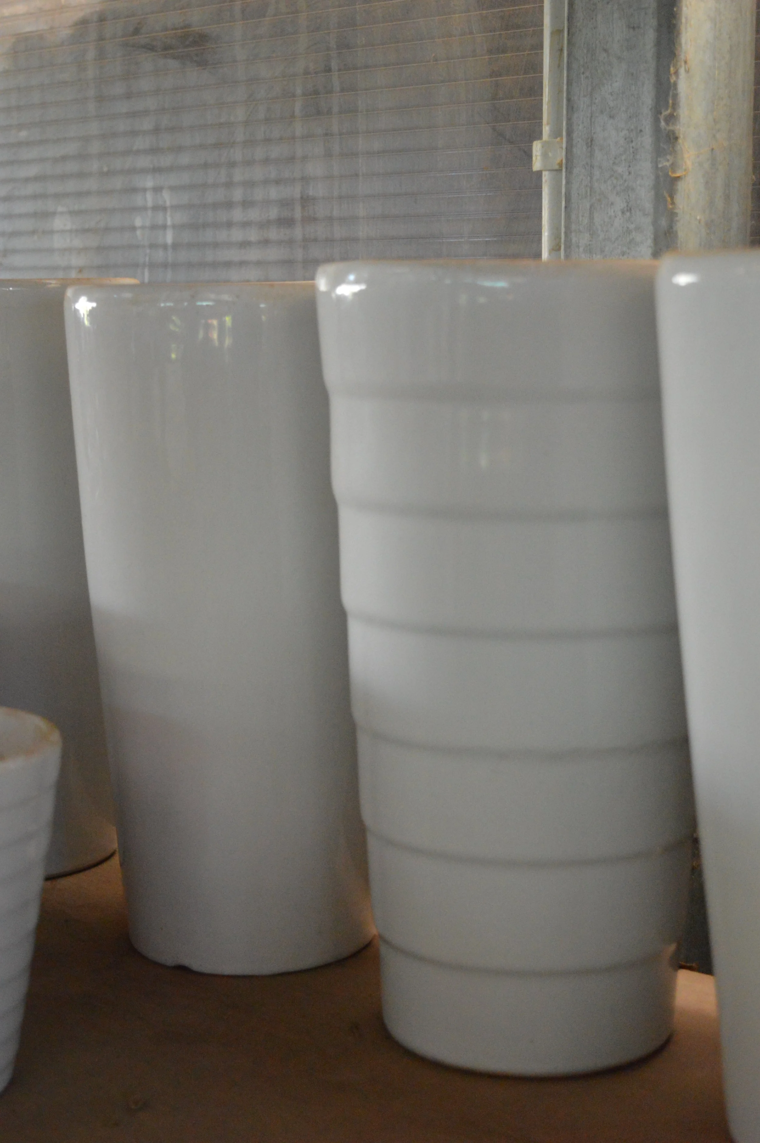 White disposable cups stacked on a wooden surface against a corrugated metal background.