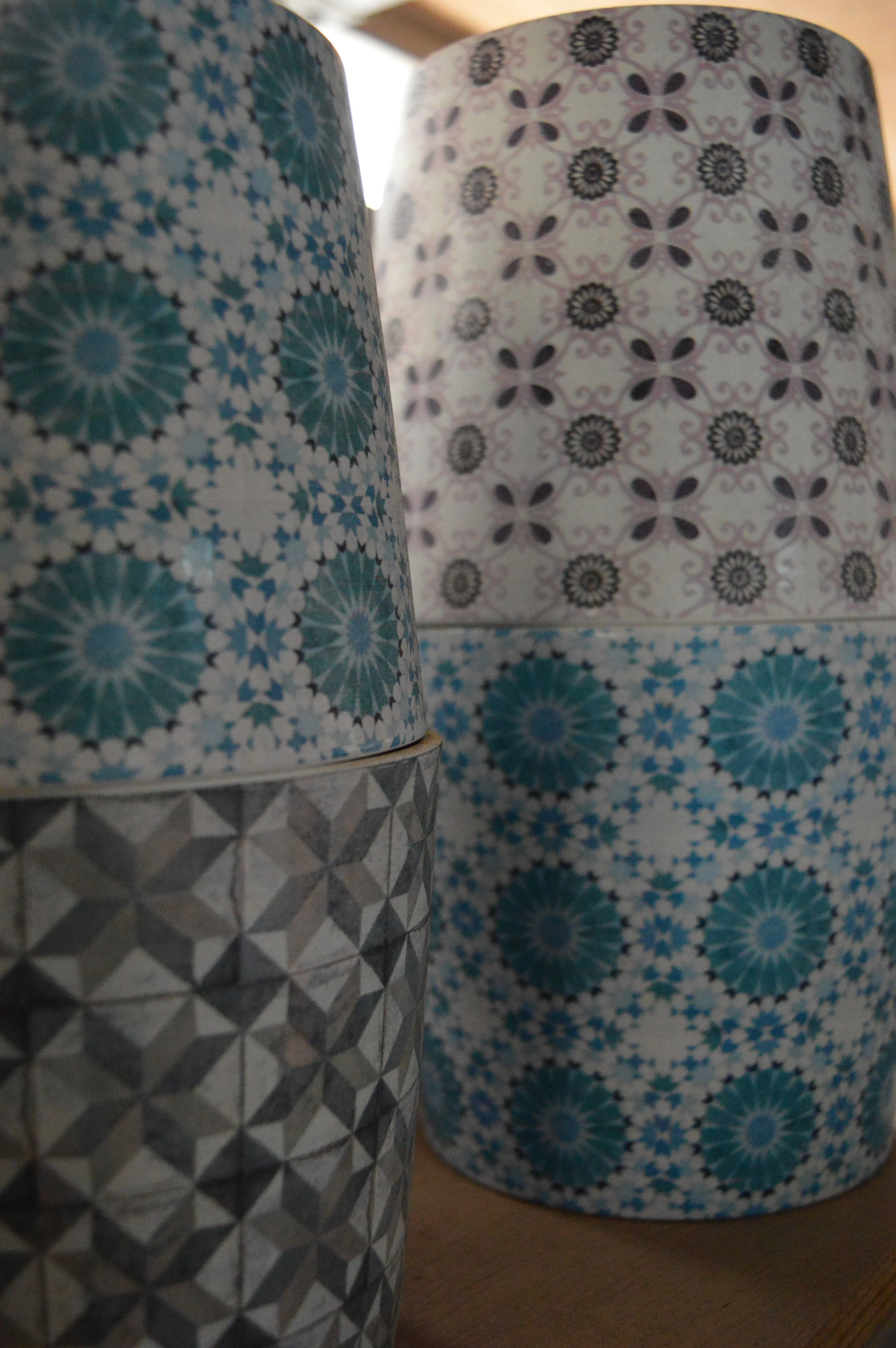 Close-up of decorative containers in blue and gray with intricate patterns, stacked on a wooden surface.