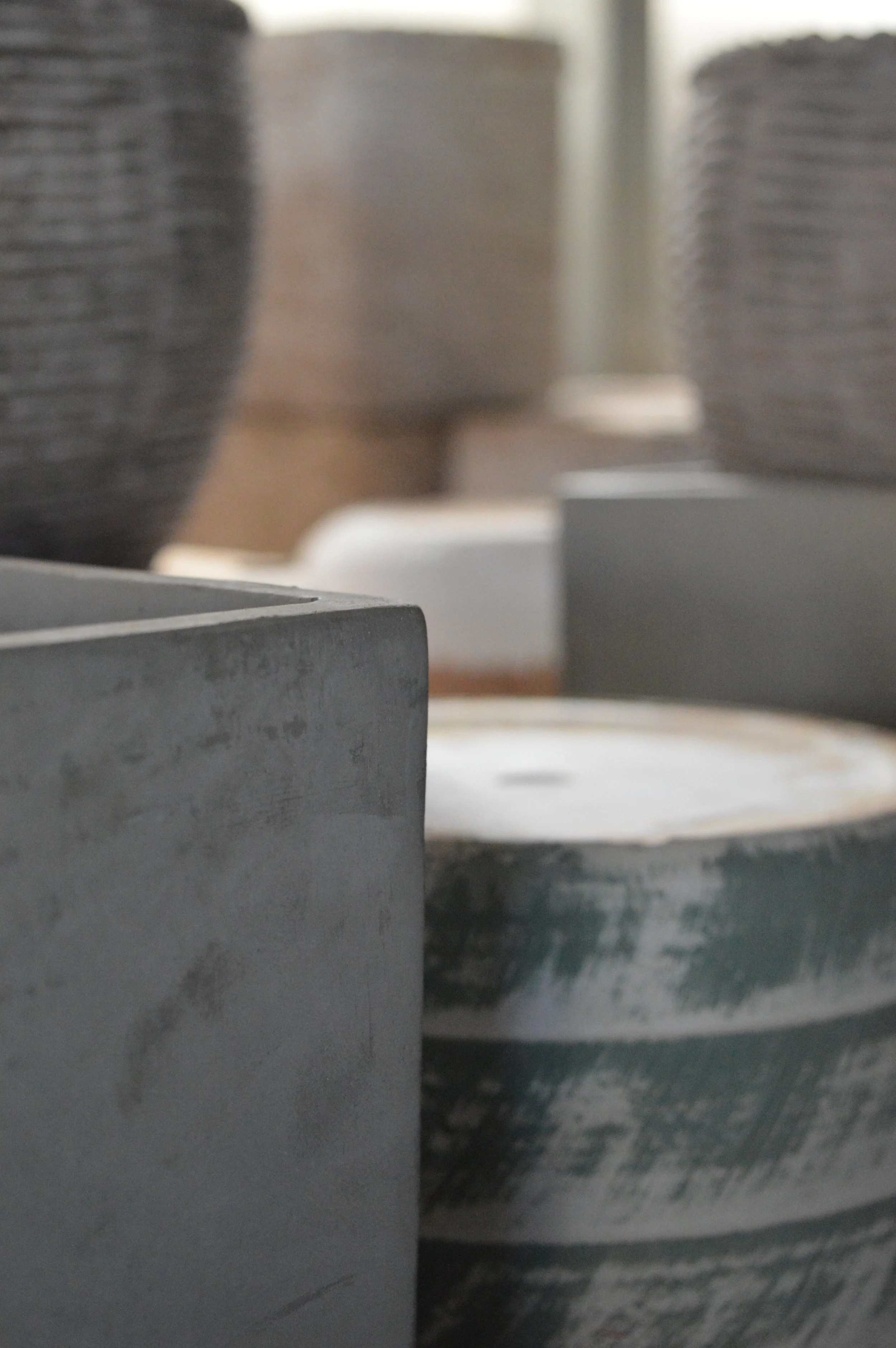Close-up view of stacked metal components, possibly machinery or industrial parts, with a focus on a dark gray, textured metal surface in the foreground.