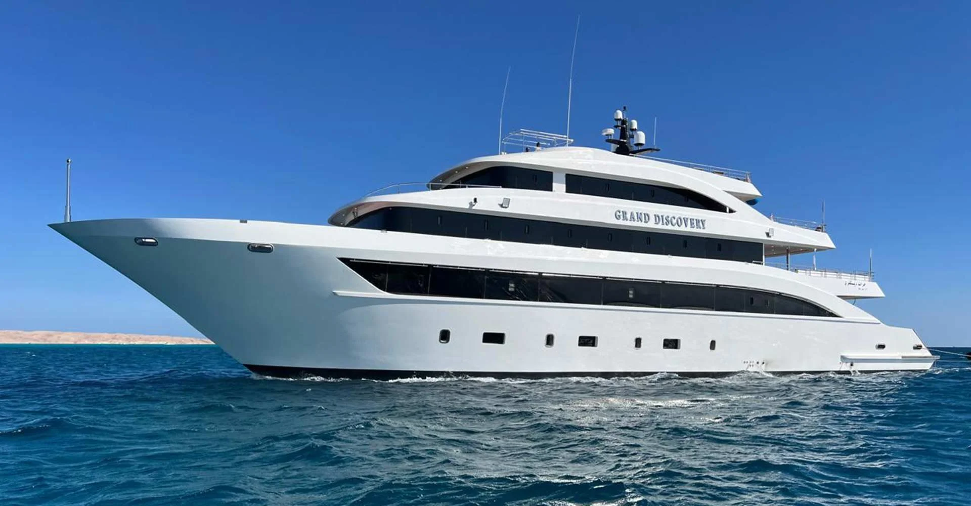 A large white luxury yacht named 'Grand Discovery' sailing on the ocean.