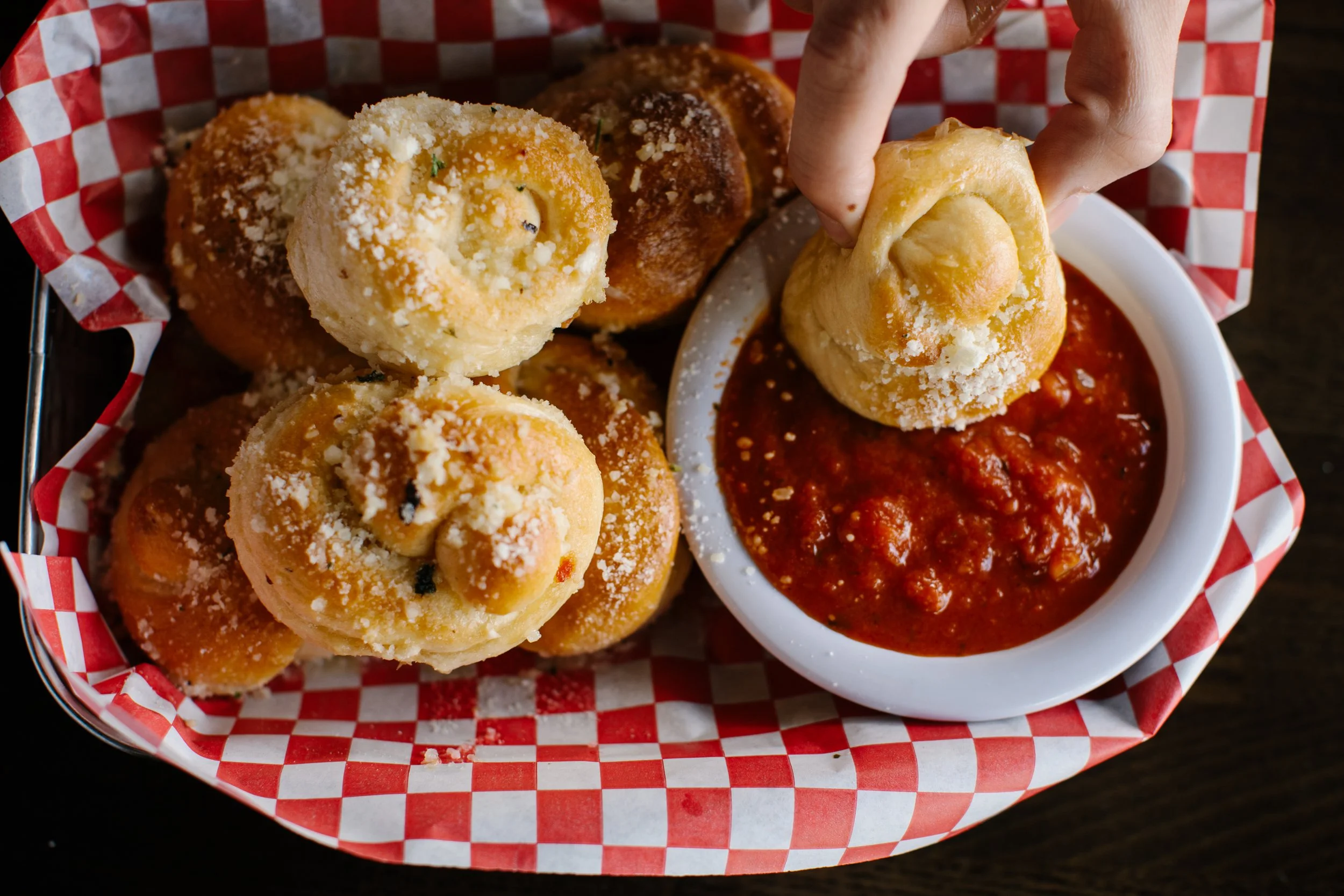 Close-up of a basket of fried cheese curds with a side of marinara sauce for dipping.