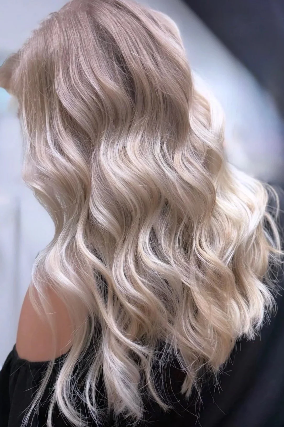 Back view of a woman with long, wavy, platinum blonde hair.