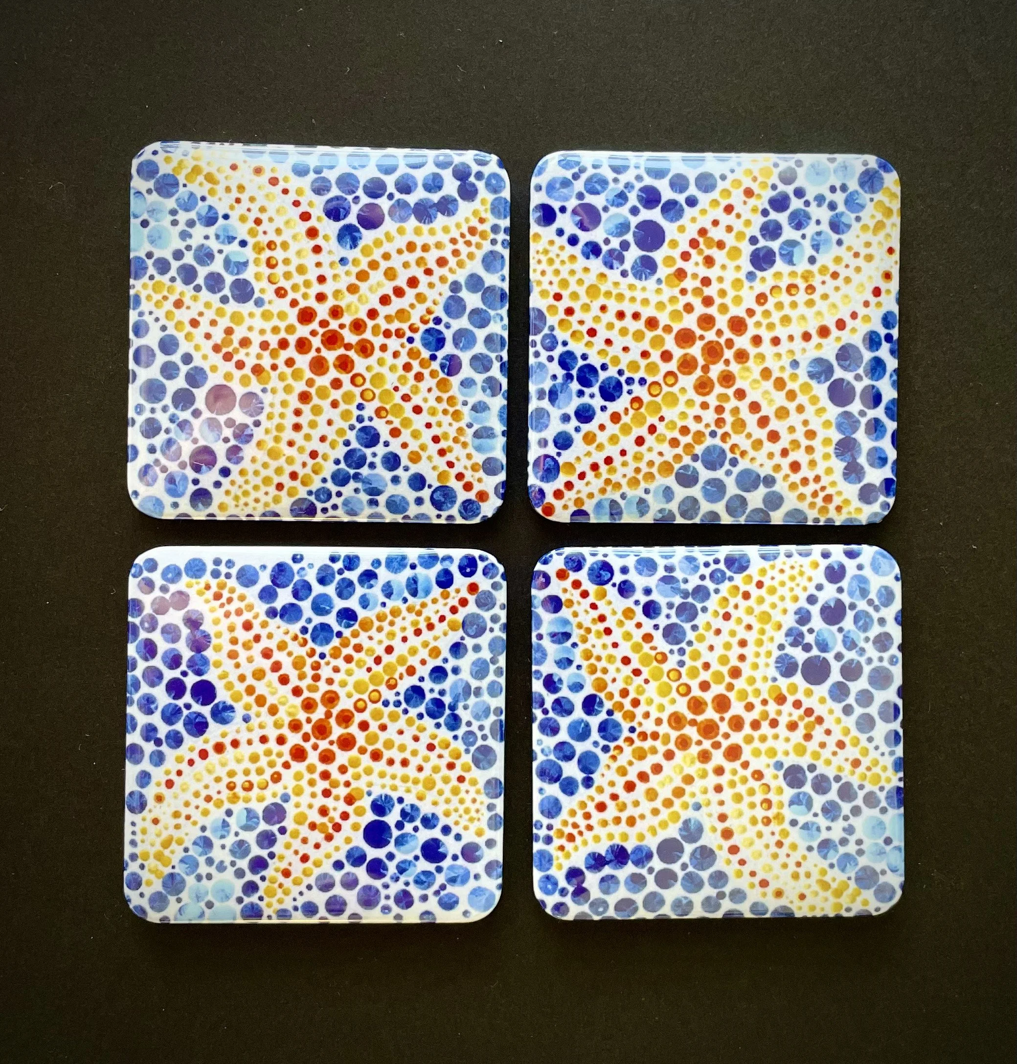 A pair of showing off colorful dot-patterned playing cards with a sparkly design on a black surface.
