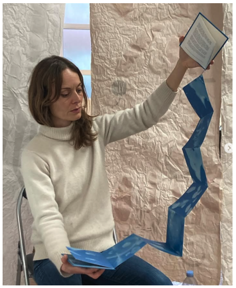 Eliza holding "As I listen I am led' book of seanotypes, London, 2024