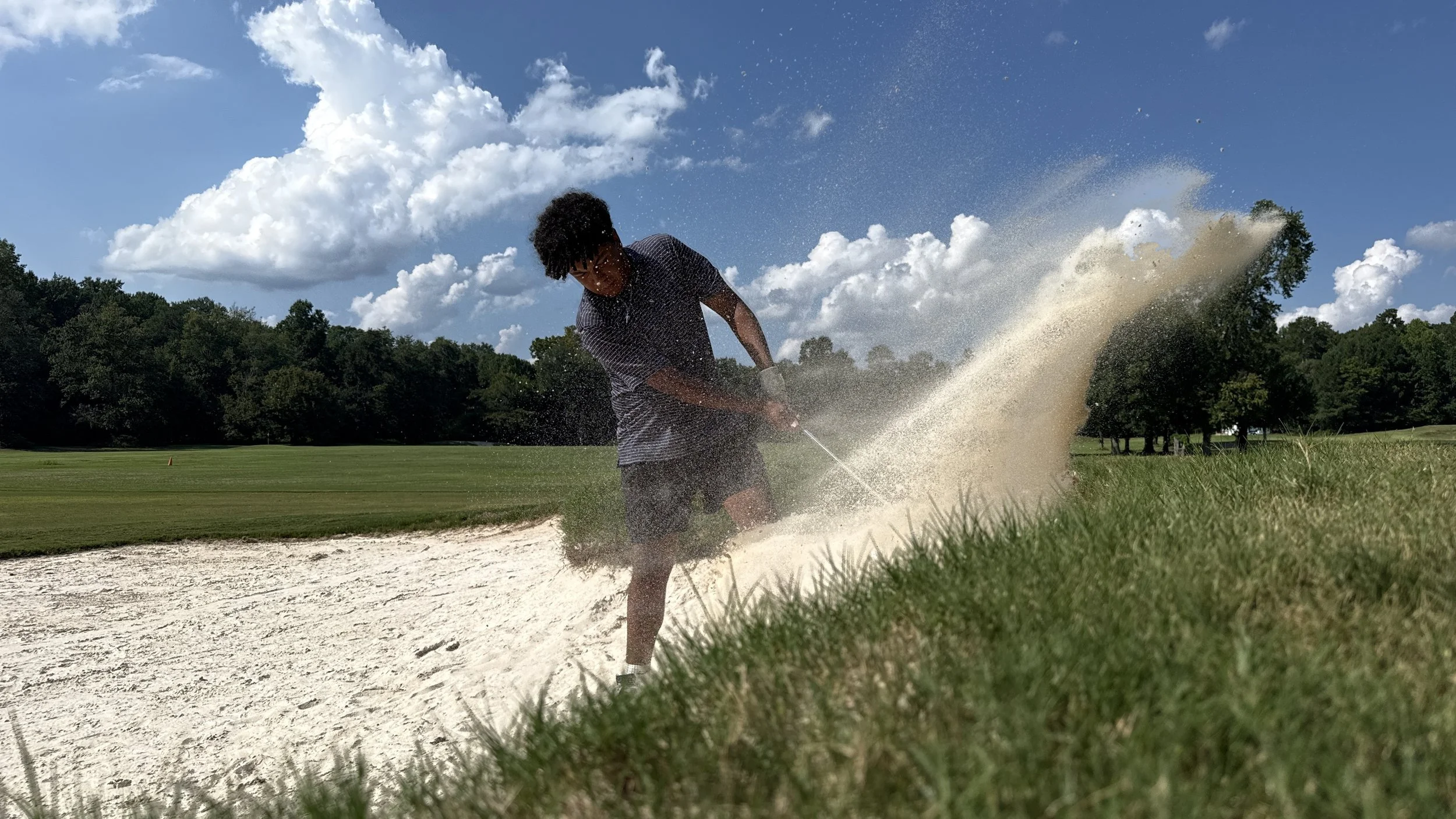Gabriel Aldama hitting a golf shot from a sand bunker.