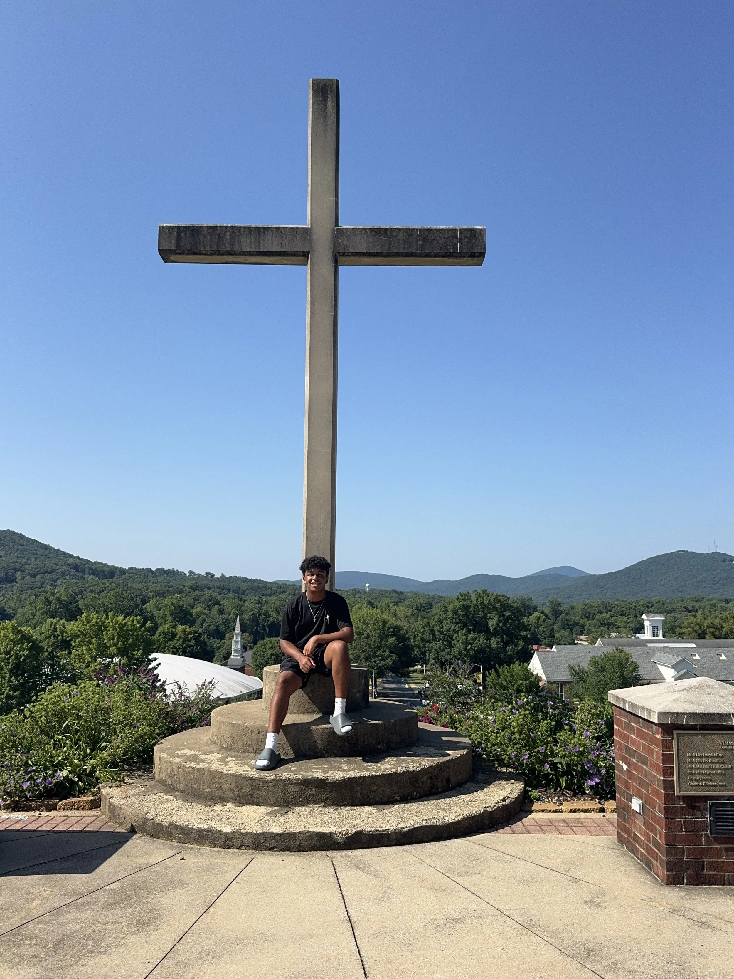 Gabriel Aldama sitting near a large outdoor cross.