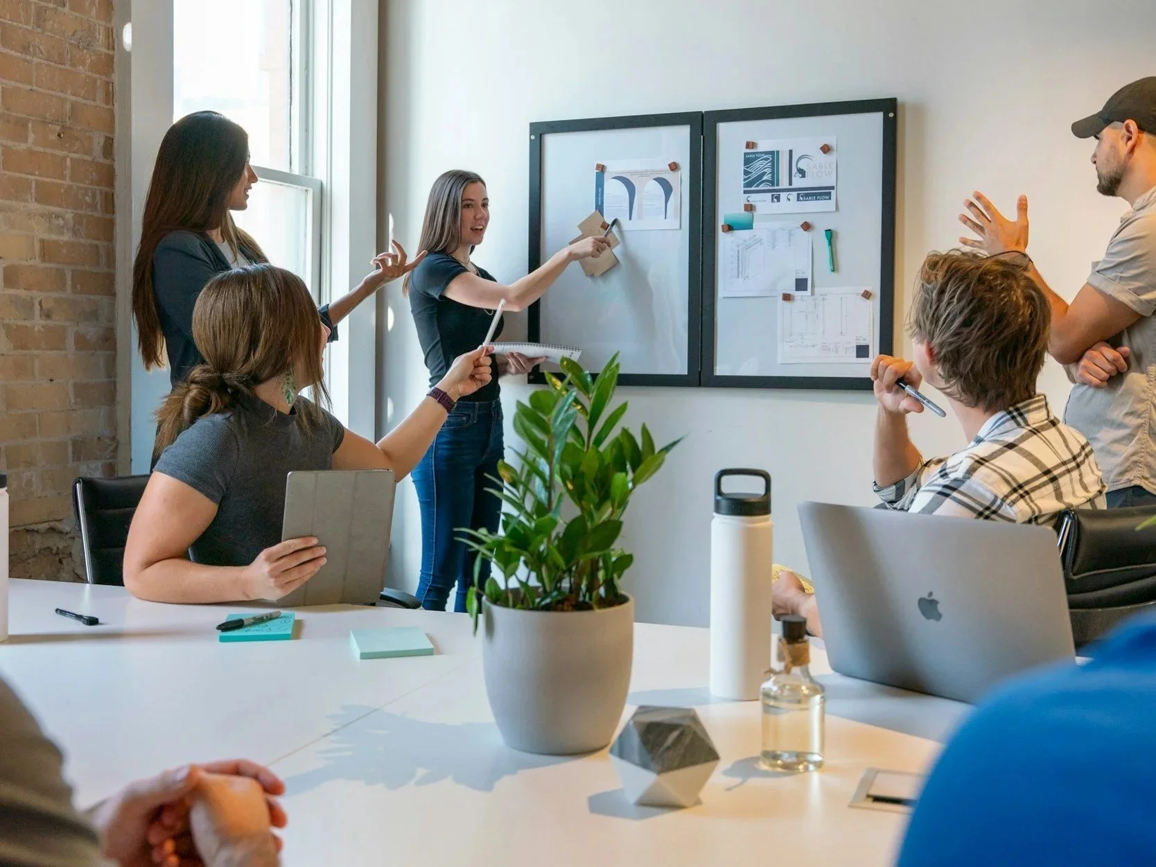 Team meeting around a table with presentation screens in the background.