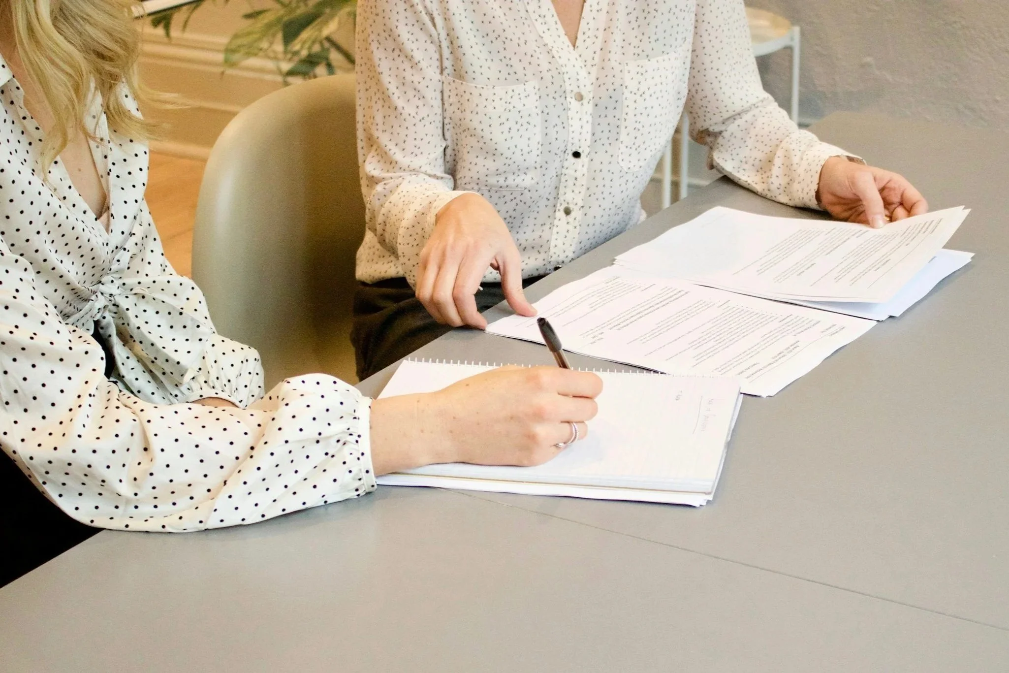 Two people working together on notes and planning documents at a table.