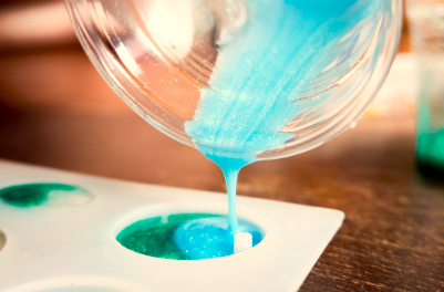 Blue paint being poured into a mold on a white tray.