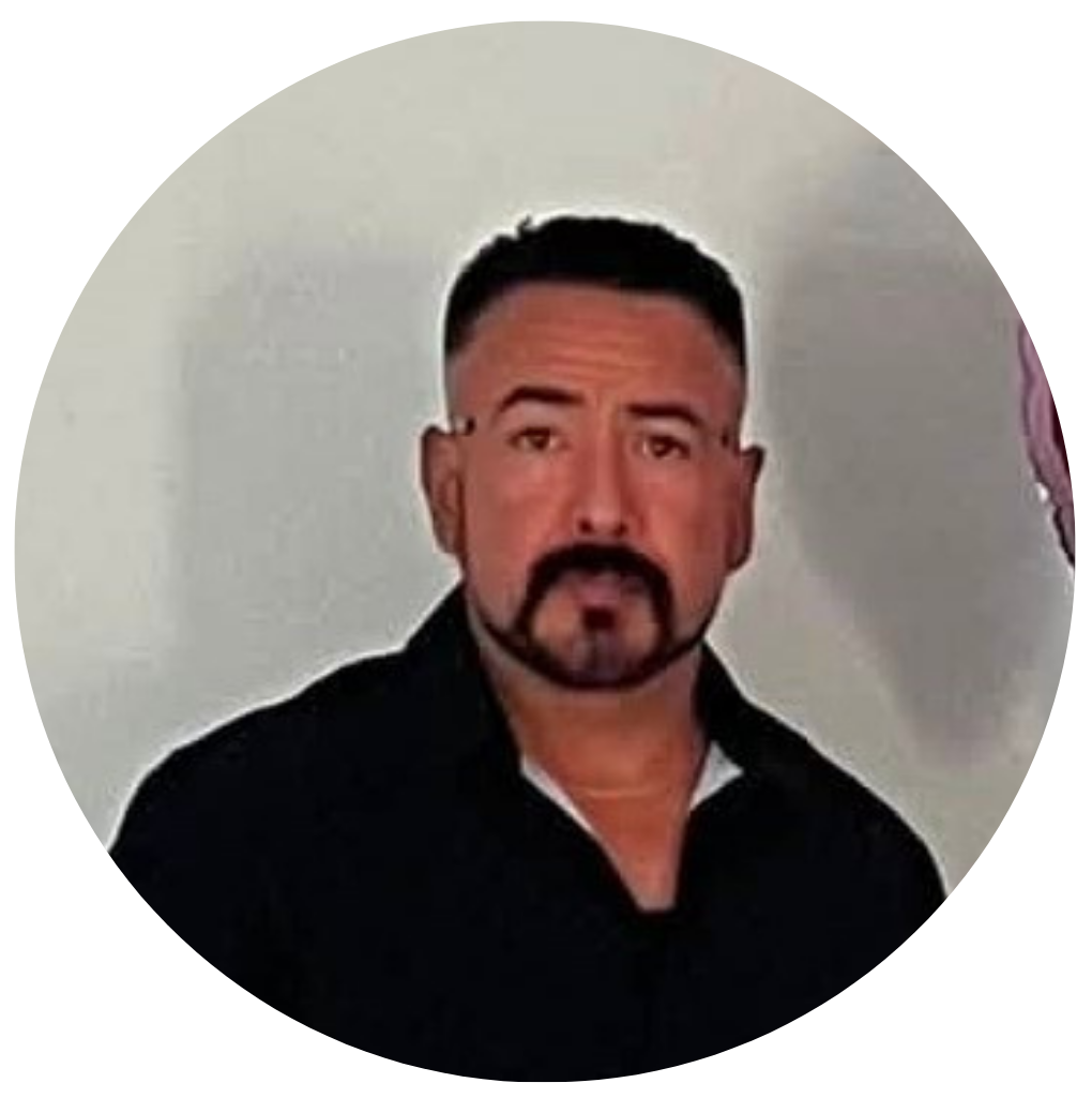 Retrato de un hombre con barba y barba de chivo, con cabello corto, usando camiseta negra, en un fondo de pared blanca.
