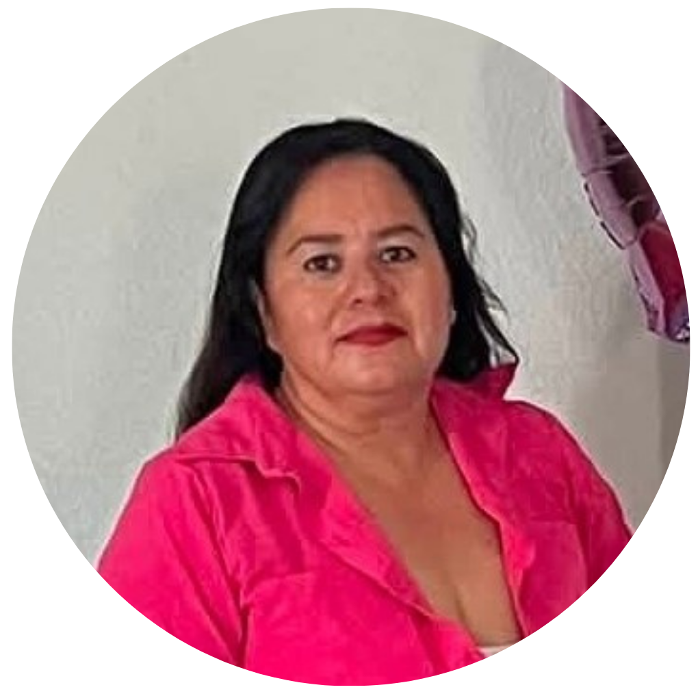 Mujer con cabello oscuro y piel morena, vestida con blusa rosa, posando frente a una pared blanca, con globos de color rosa a su lado.