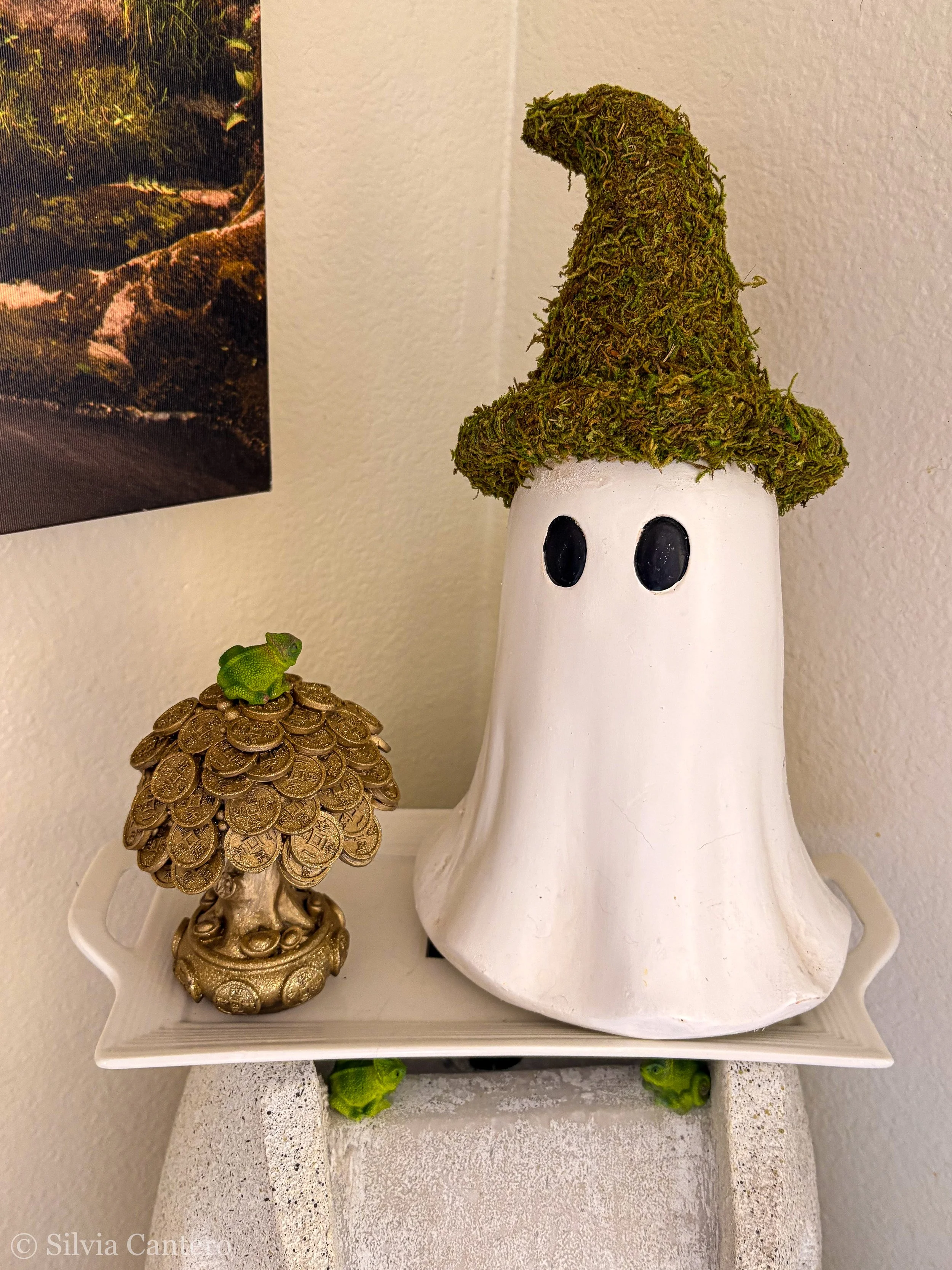 Decorative ceramic objects shaped like a mushroom and a tree. The mushroom is white with black eyes, and the tree has a golden trunk and a green, moss-like top.