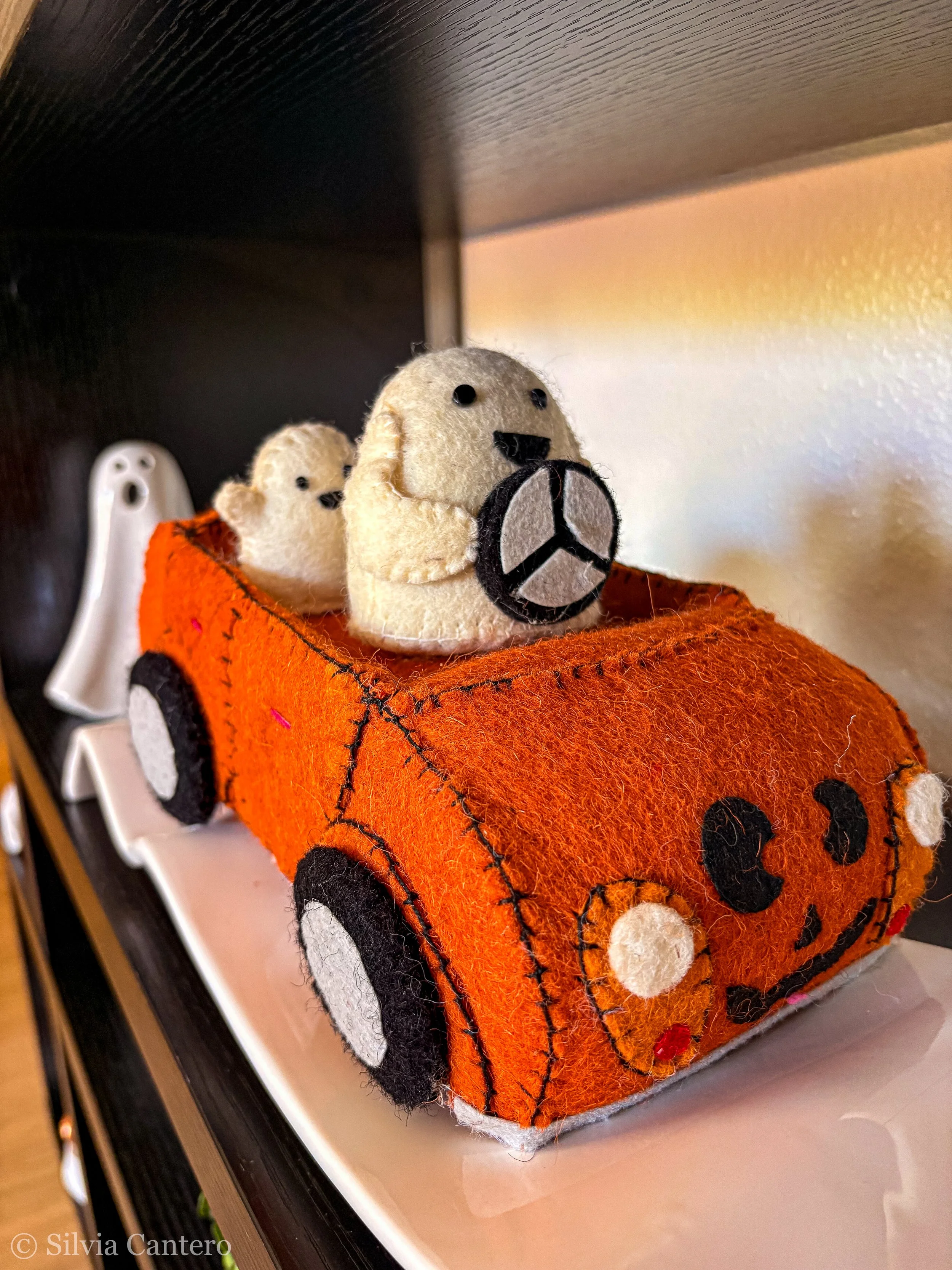 Felted pumpkin with a white bear holding a black and white soccer ball on top of an orange felt pumpkin decoration.