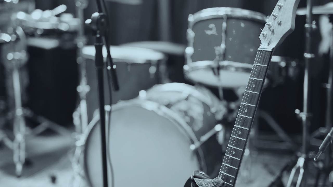 A music rehearsal space with a guitar, drum set, and microphones.
