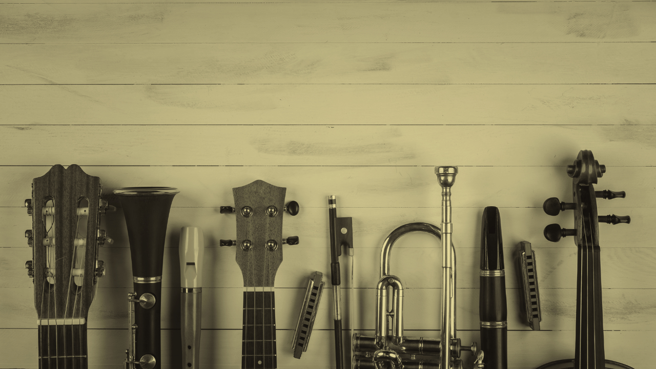 A lineup of musical instruments and a harmonica against a wooden background.