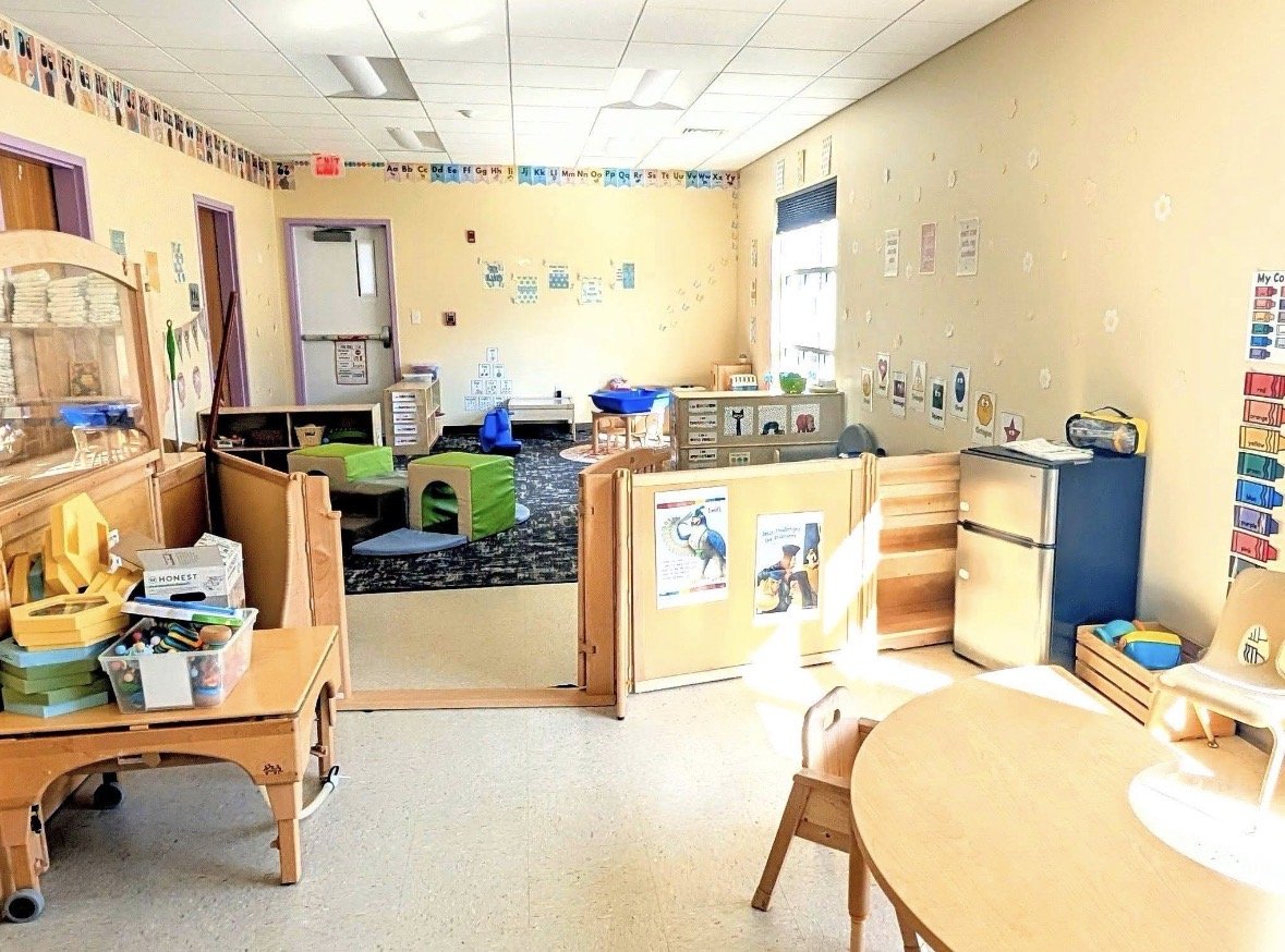 An early childhood classroom with colorful decorations, small furniture, and educational materials for young children.