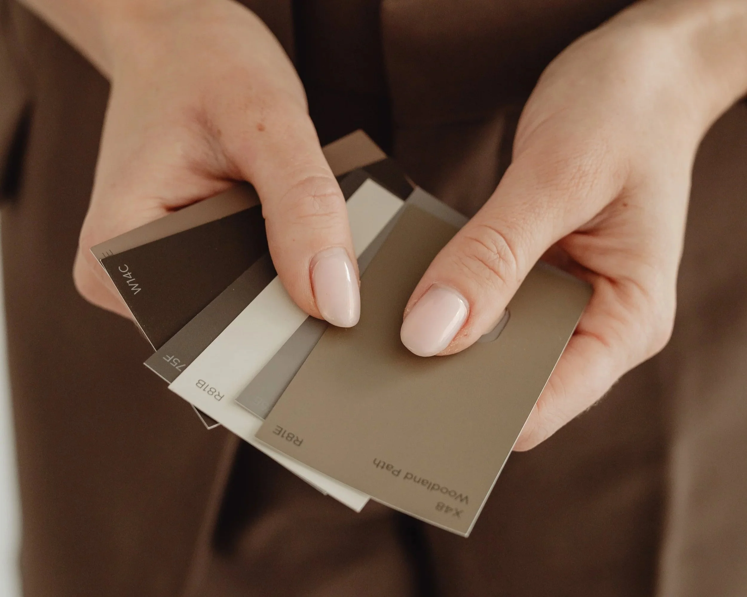 Interior designer holding neutral paint and finish swatches