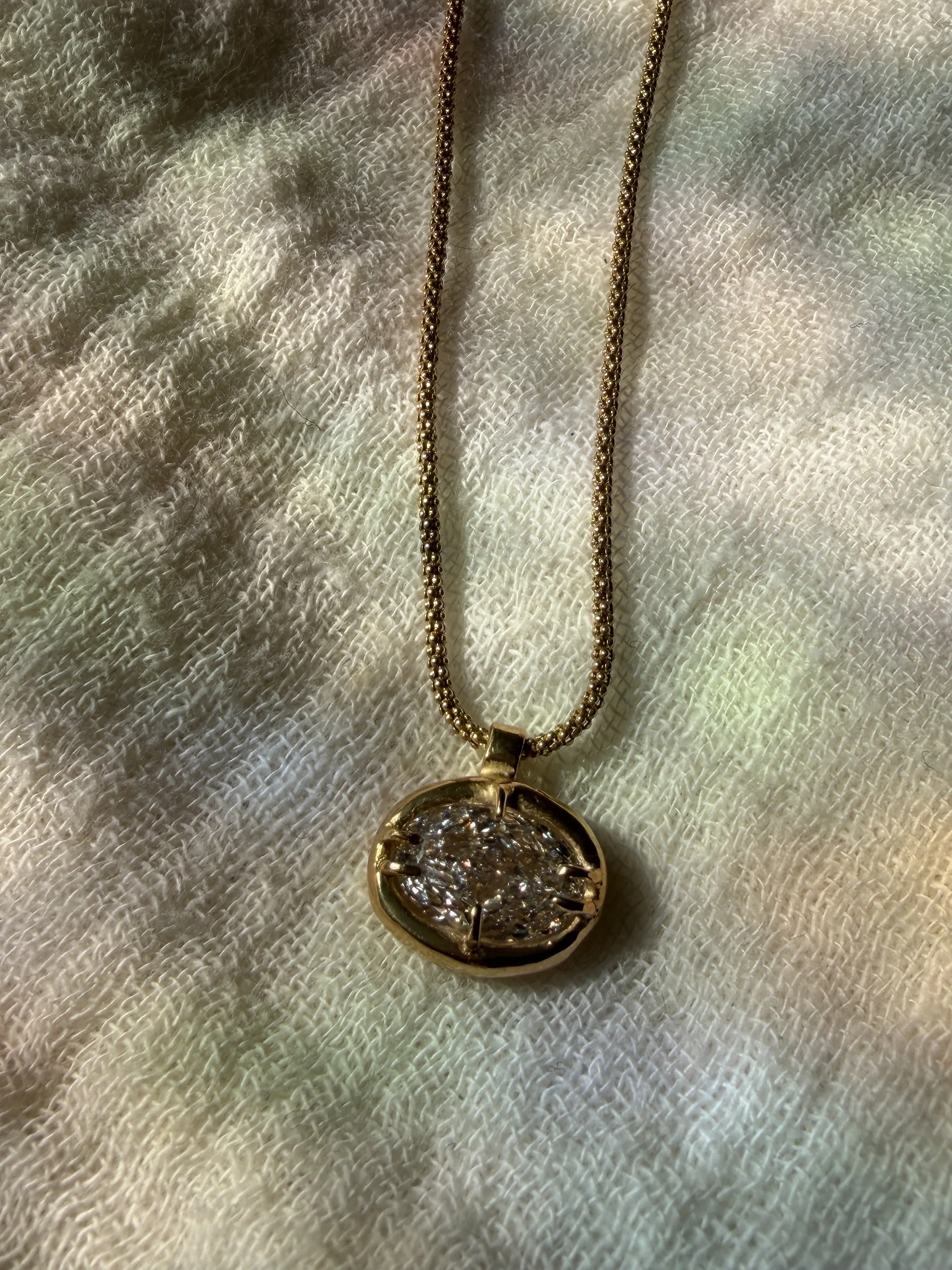 18k 9k yellow gold necklace with oval-cut white diamond pendant in an organic claw setting.