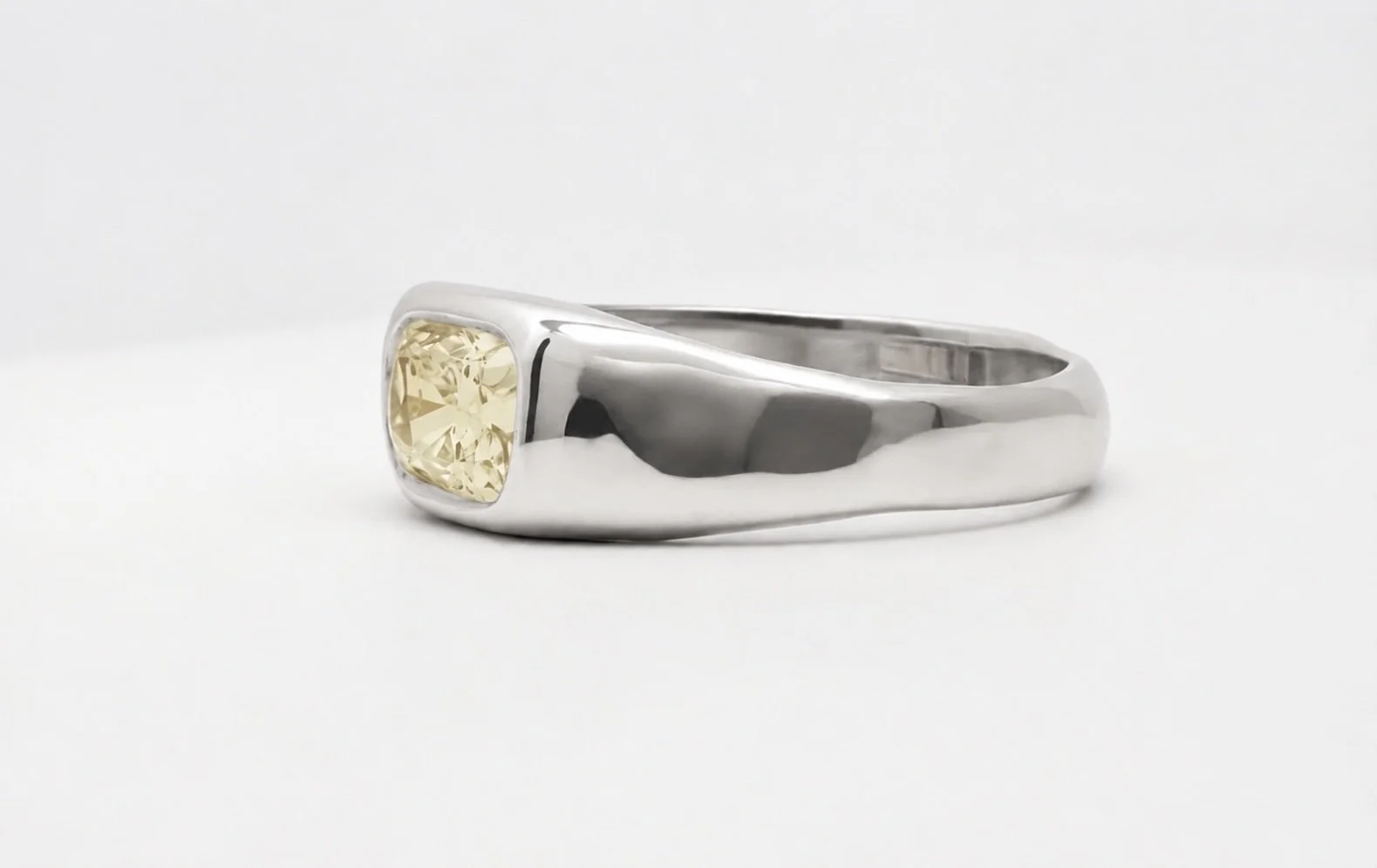 Organic 18k white gold ring with pale yellow elongated cushion-cut lab-grown diamond in a bezel setting.