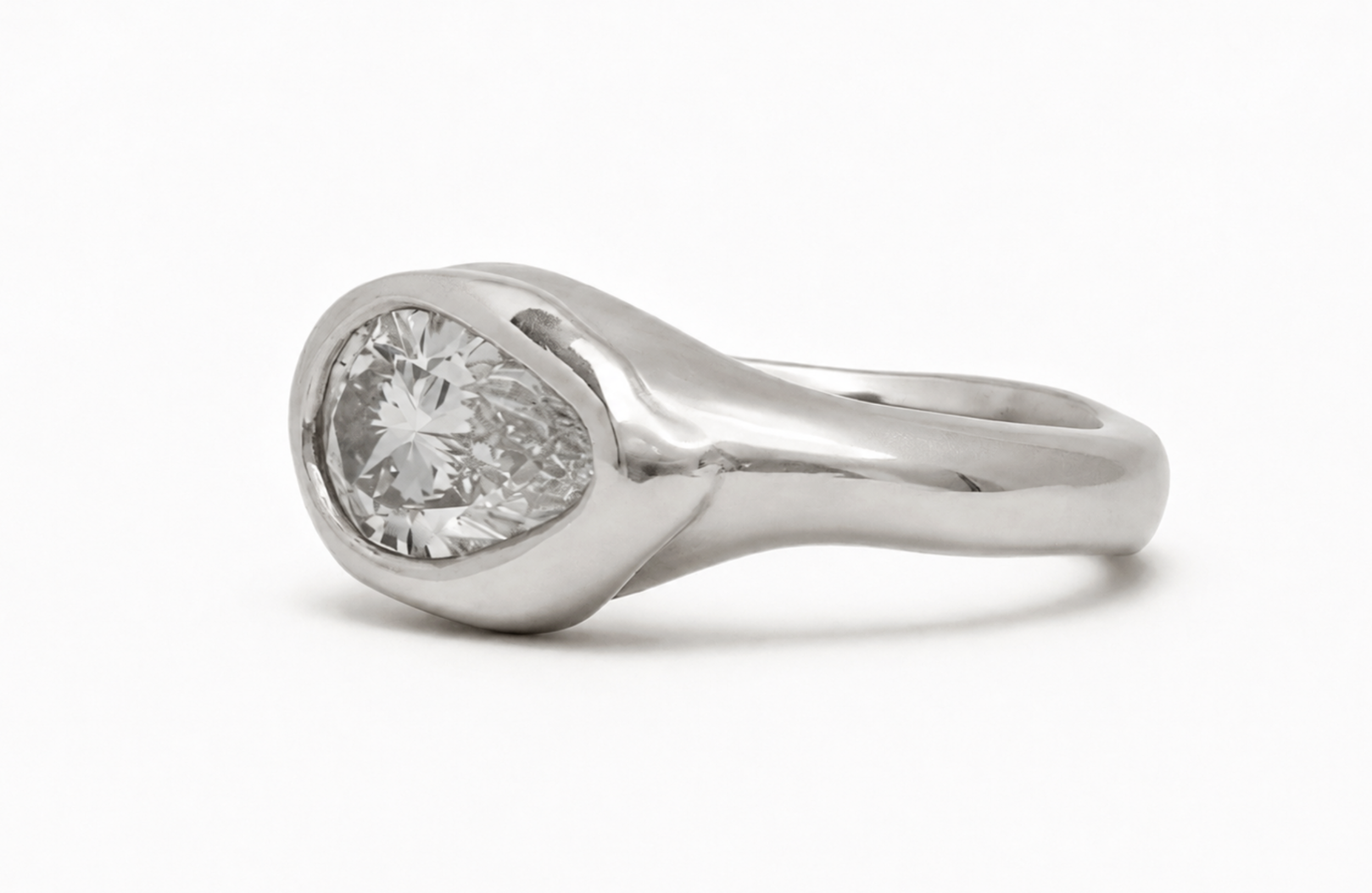 18k white gold ring with pear-cut lab-grown diamond in an organic bezel setting on a white background.