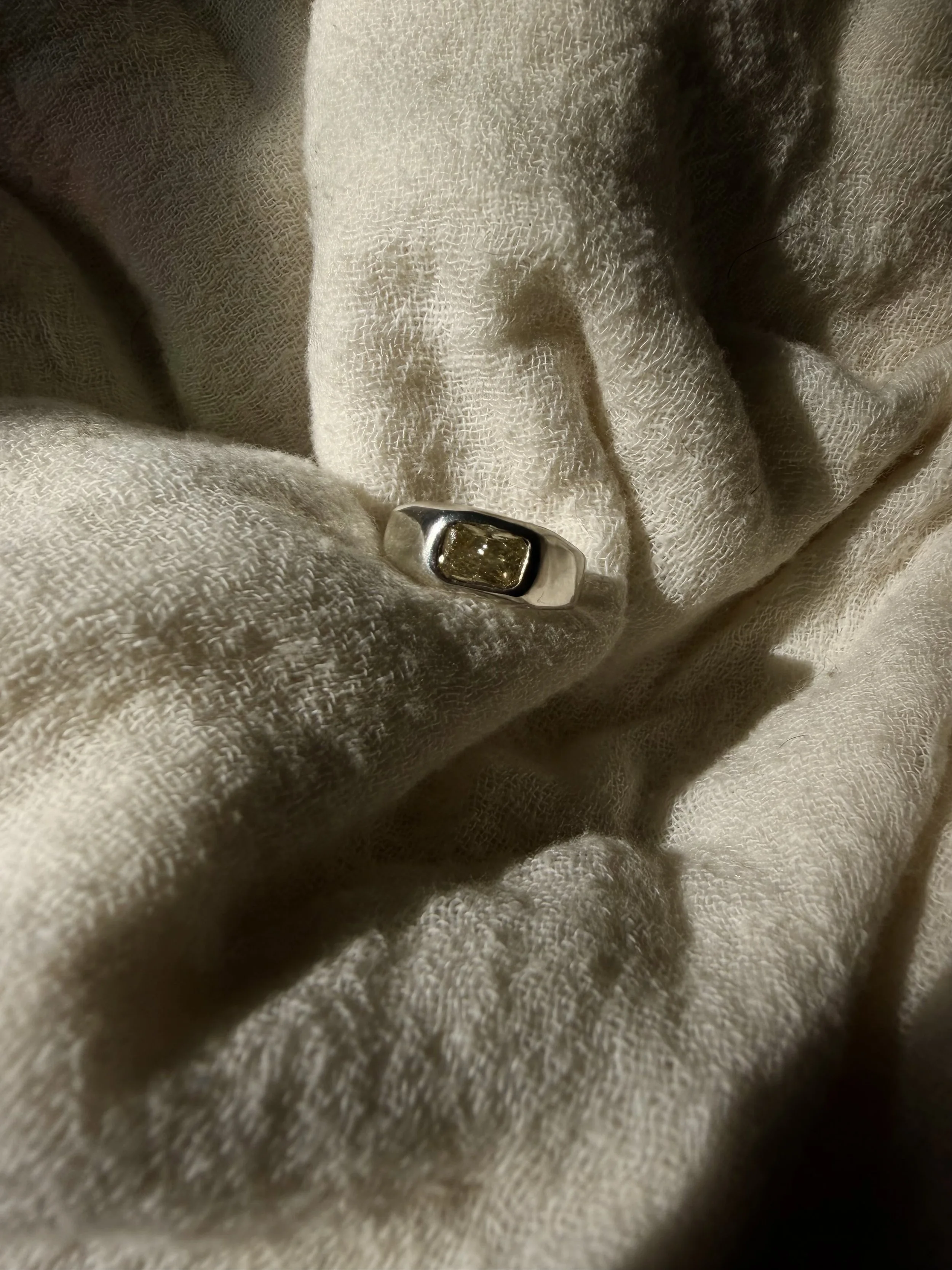 Organic 18k white gold ring with pale yellow elongated cushion-cut lab-grown diamond in a bezel setting.