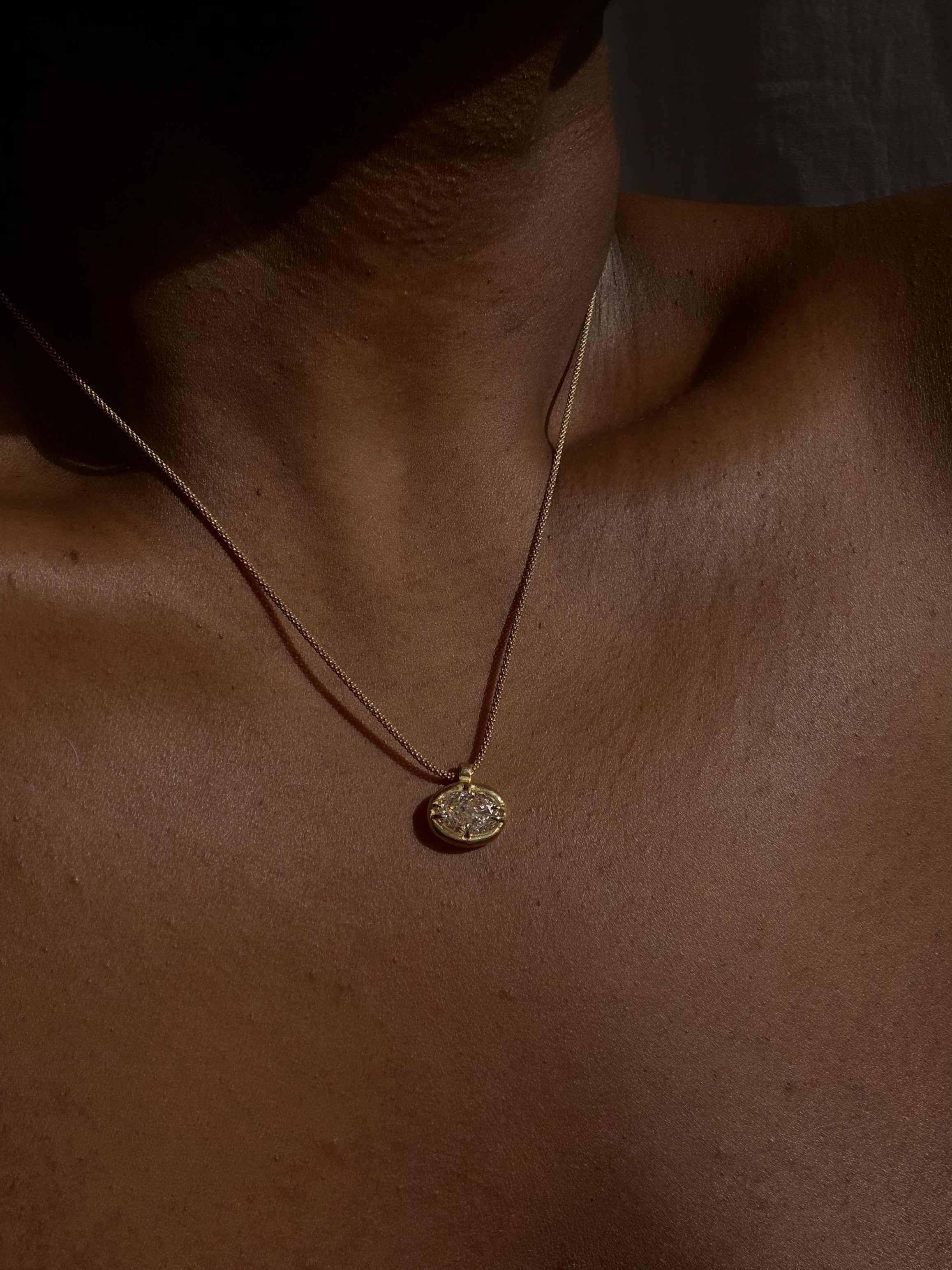 18k 9k yellow gold necklace with oval-cut white diamond pendant in an organic claw setting.