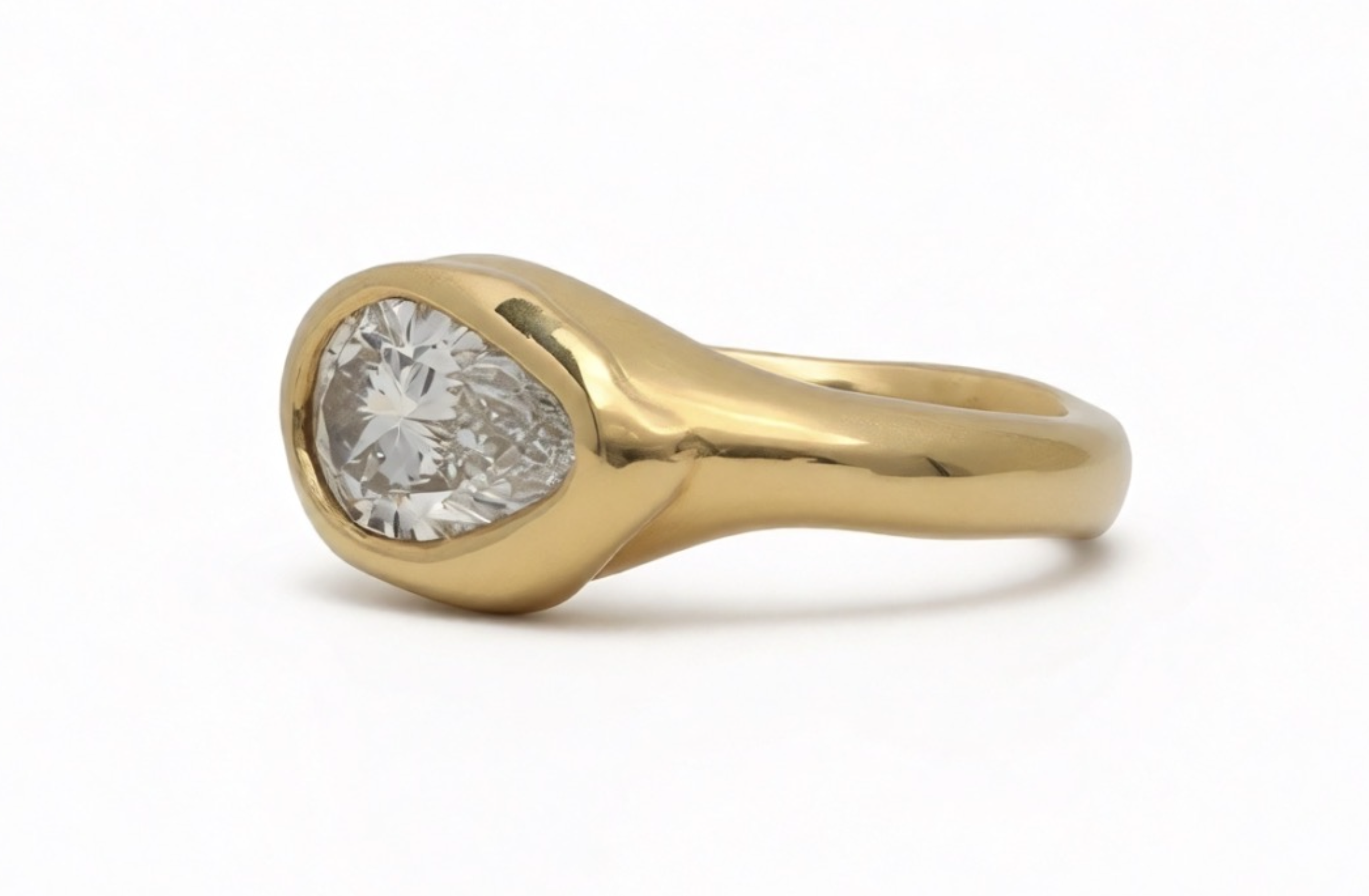 18k yellow gold ring with pear-cut lab-grown diamond in an organic bezel setting .