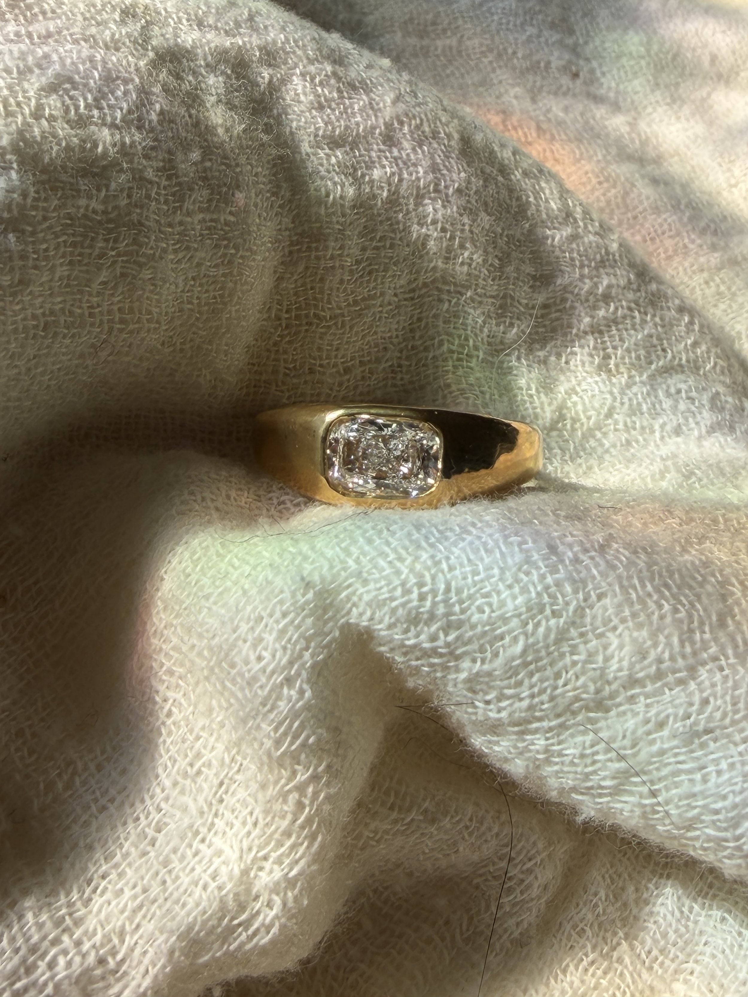 Polished 18k 9k yellow gold ring with elongated cushion-cut white diamond in an organic bezel setting