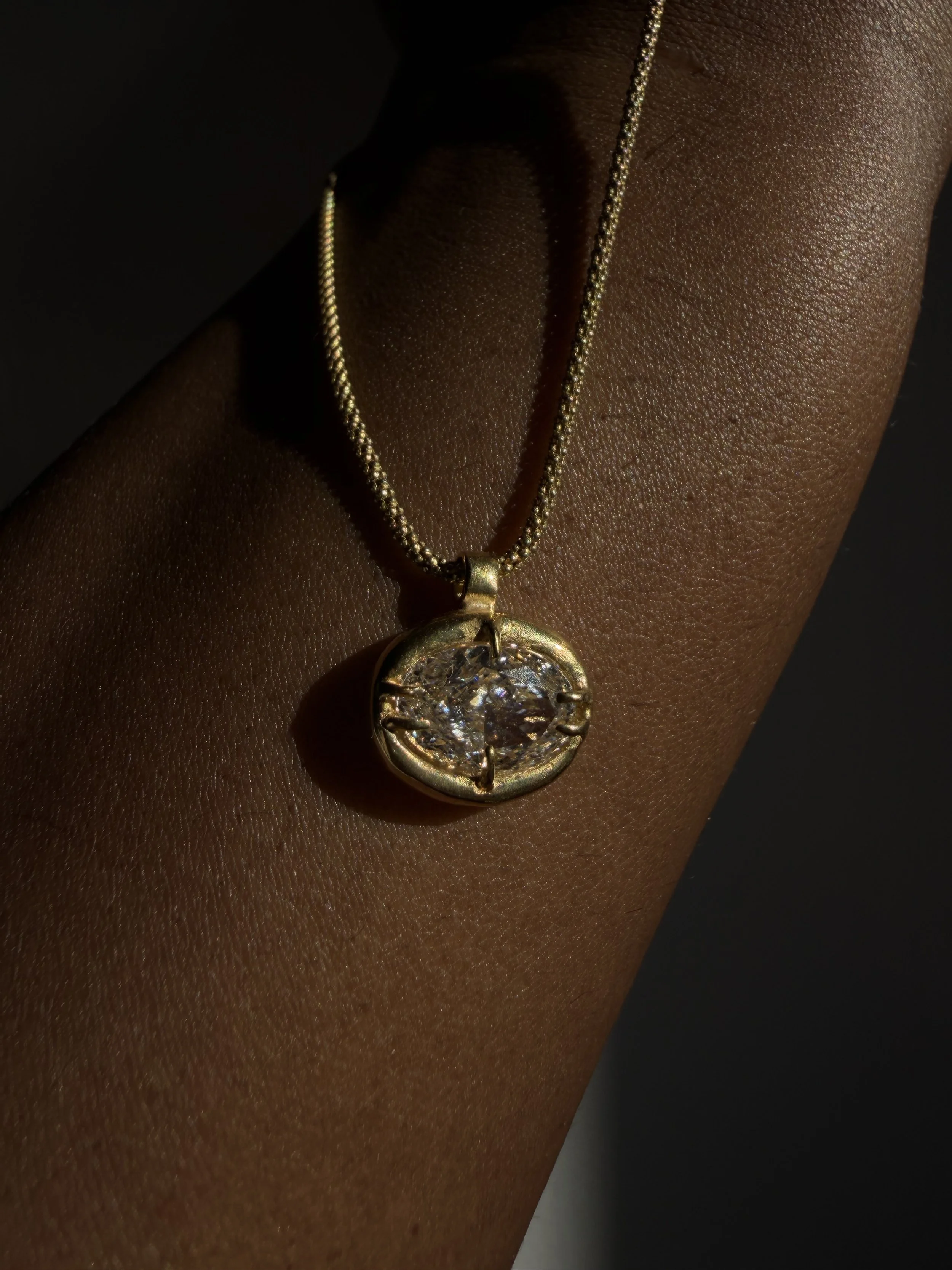 18k 9k yellow gold necklace with oval-cut white diamond pendant in an organic claw setting.