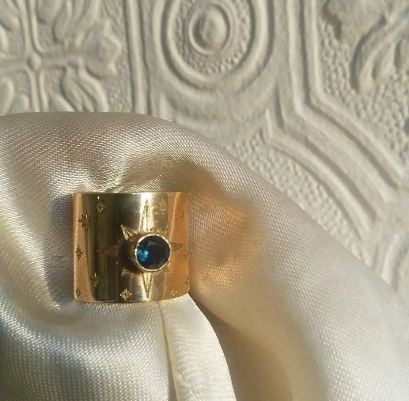 A 9k Yellow gold cuff ring with star engravings and an Australian Blue Sapphire bezel set