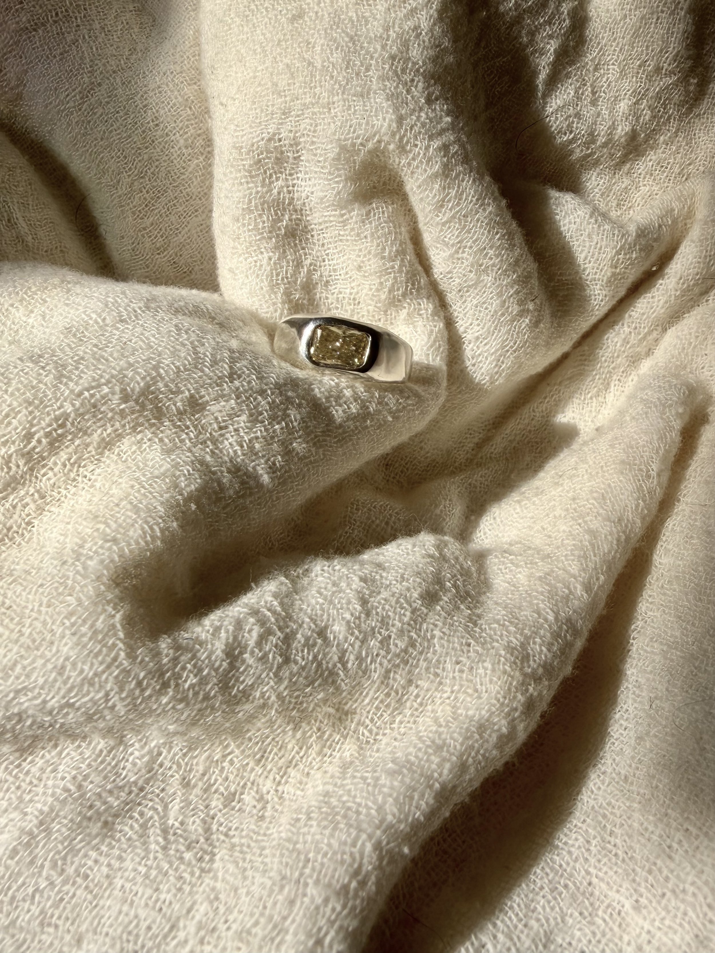 Organic 18k white gold ring with pale yellow elongated cushion-cut lab-grown diamond in a bezel setting.