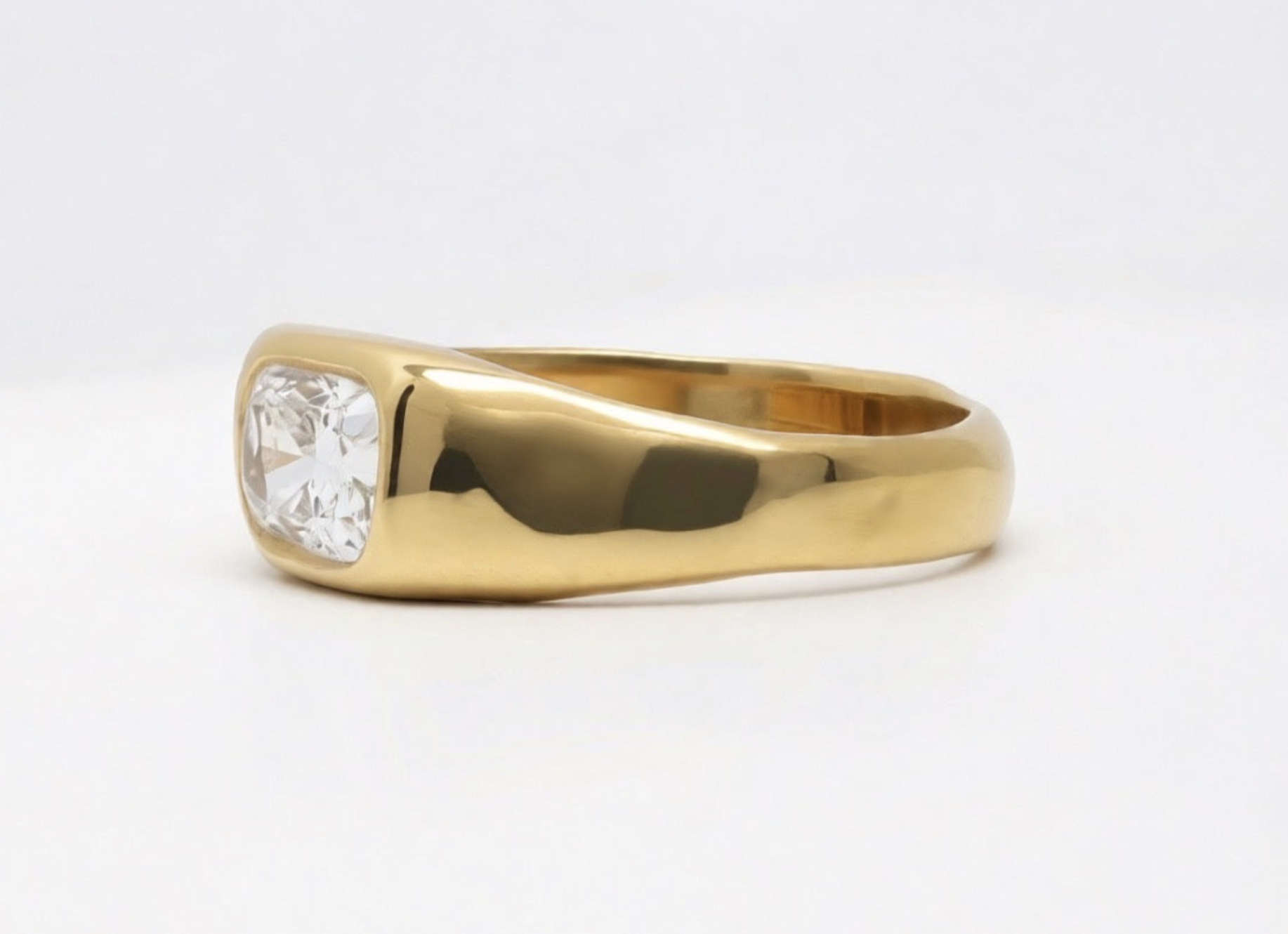 Polished 18k 9k yellow gold ring with elongated cushion-cut white diamond in an organic bezel setting