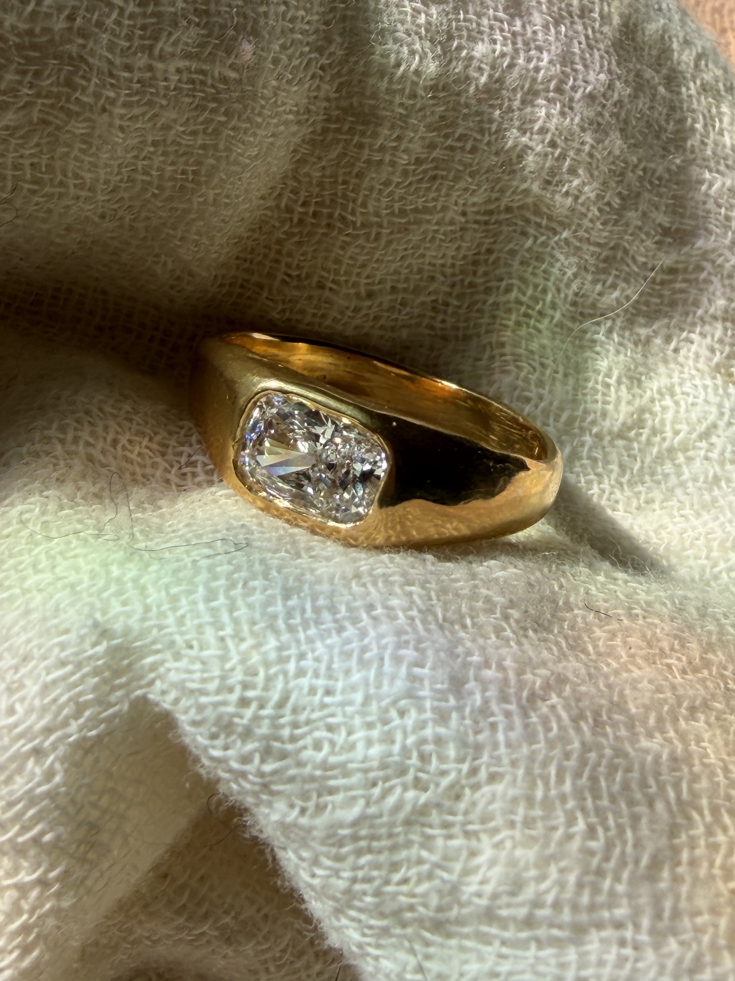Polished 18k 9k yellow gold ring with elongated cushion-cut white diamond in an organic bezel setting