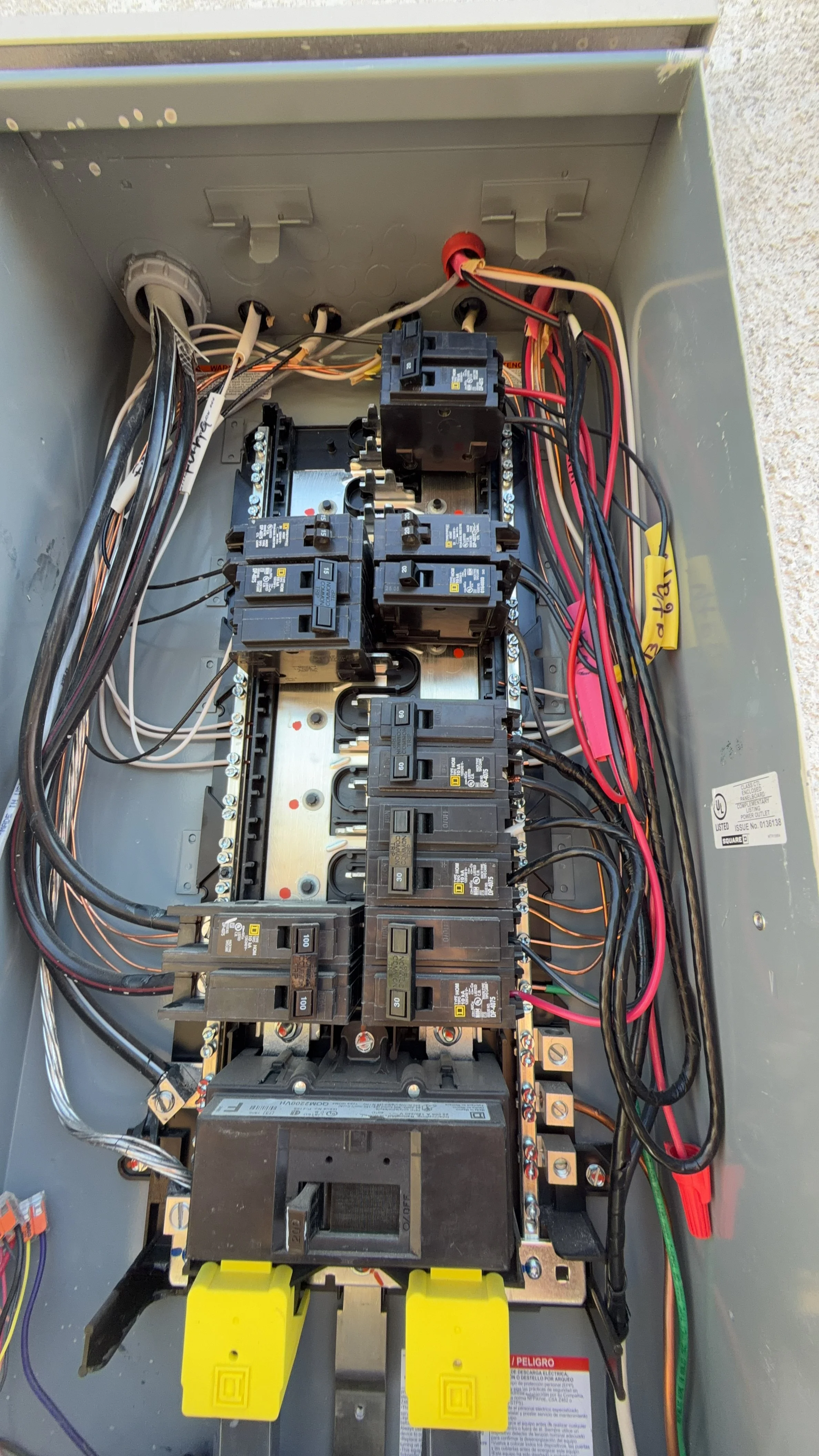 Close-up of the interior of an electrical panel with multiple circuit breakers, wires, and reset switches.