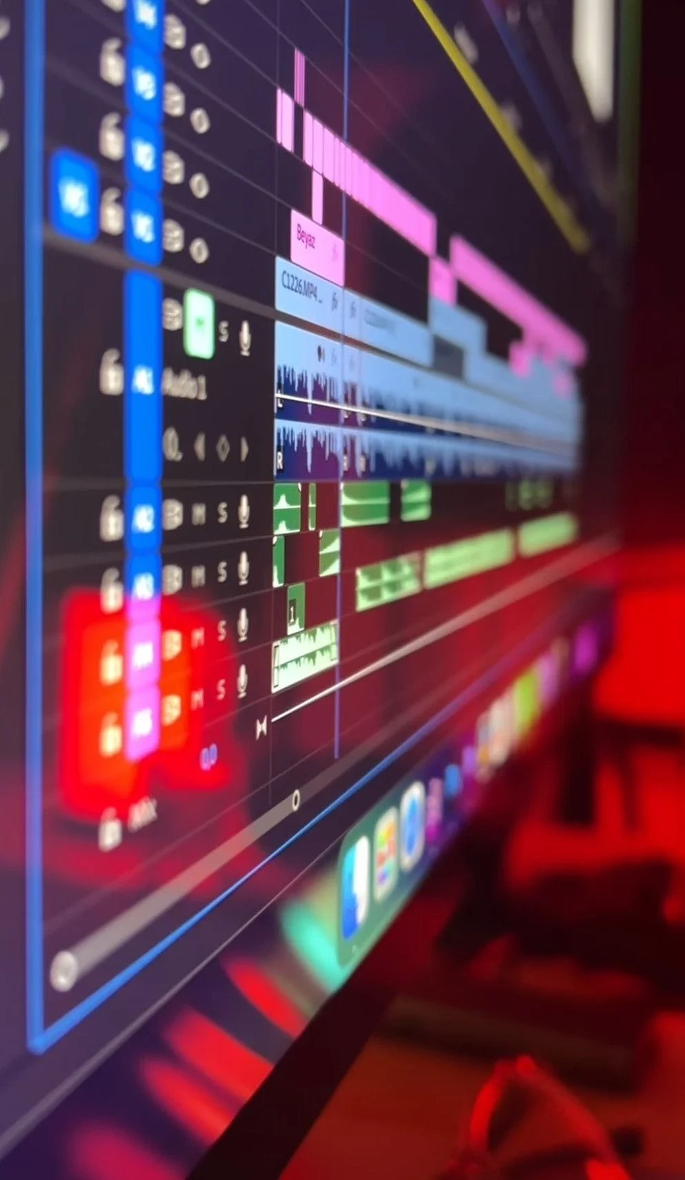 Close-up of a digital audio workstation screen displaying multiple tracks with waveforms, audio clips, and editing controls in a music production software.