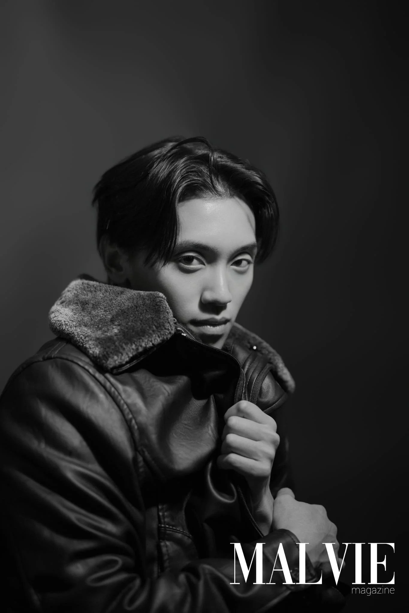 Black and white photo of a person with short dark hair, wearing a leather jacket with a fuzzy collar, looking directly at the camera. The photo is part of a magazine cover titled 'MALVIE'.
