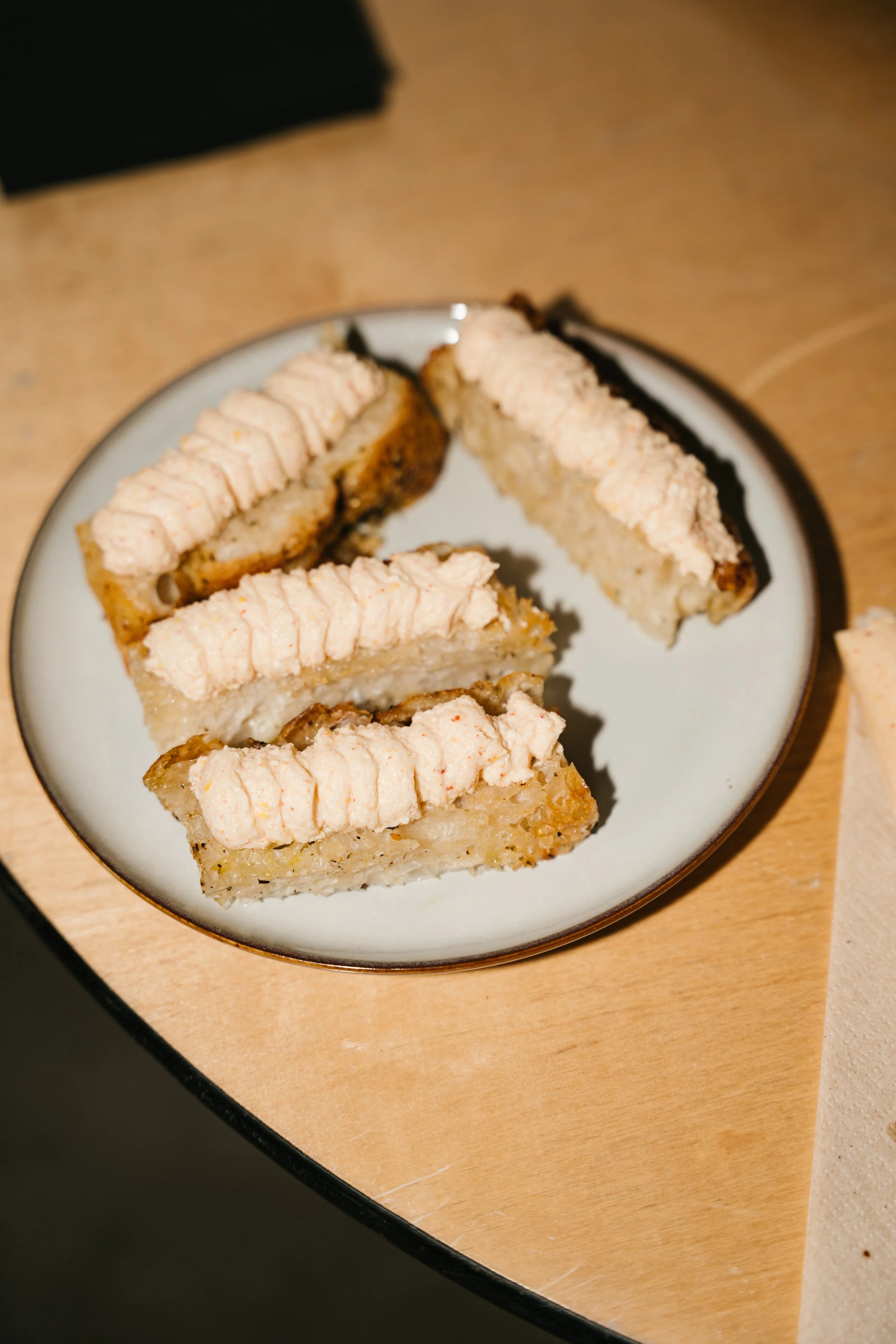 Close-up view of sushi pieces on a round plate on a wooden table, with a blurred background.