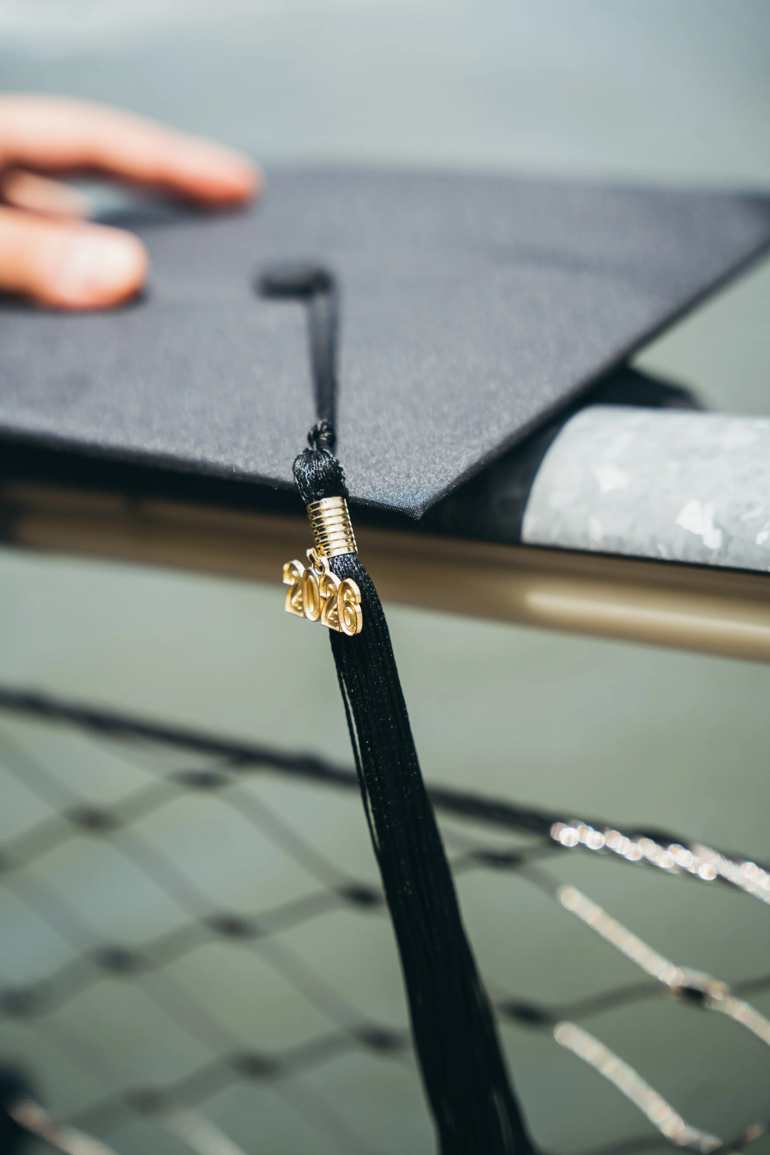 Close-up of a black graduation cap with a gold necklace that has the year 2026 on it, hanging from the cap's tassel.