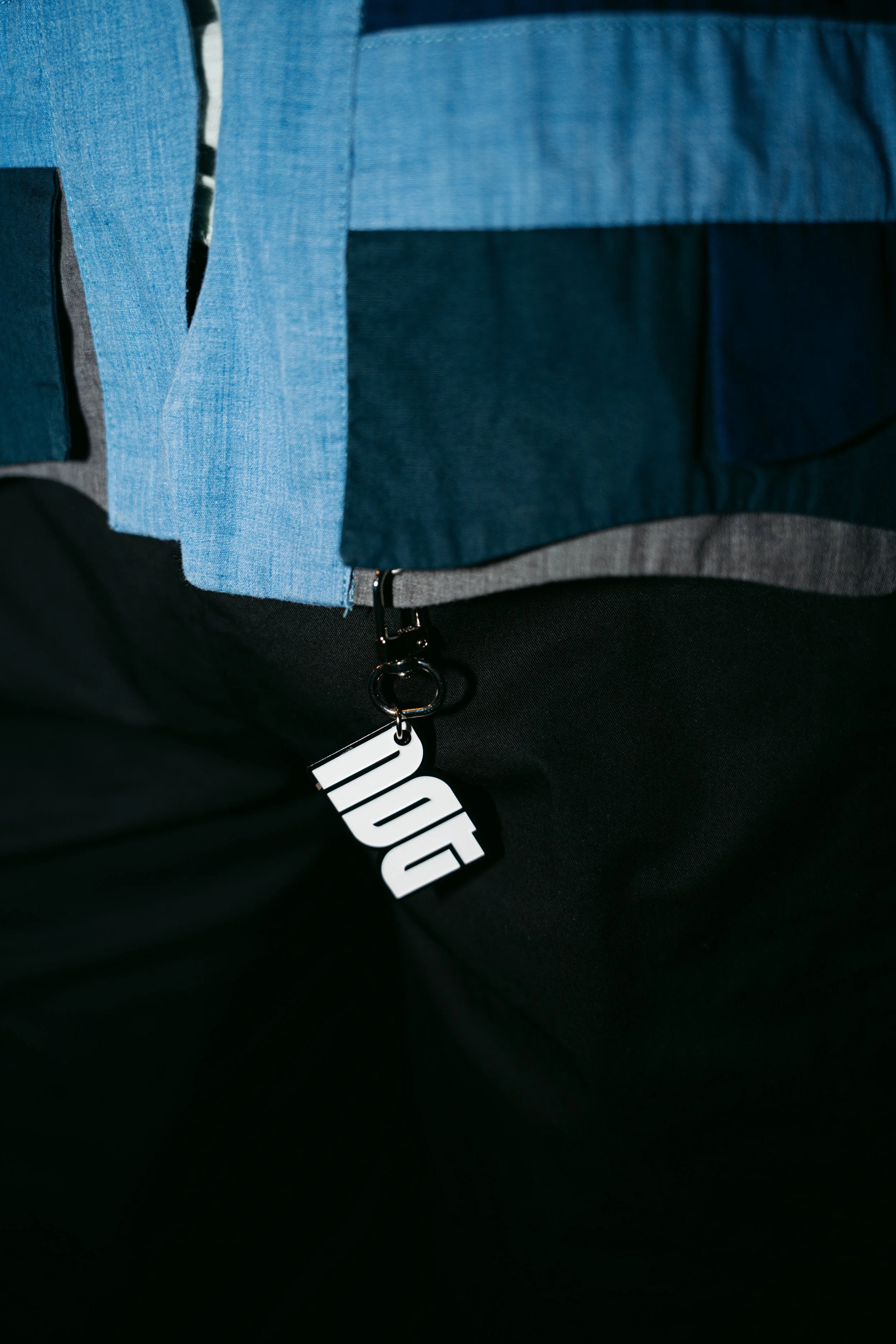 Close-up of a blue backpack with black accents and a white tag that says 'DO'.