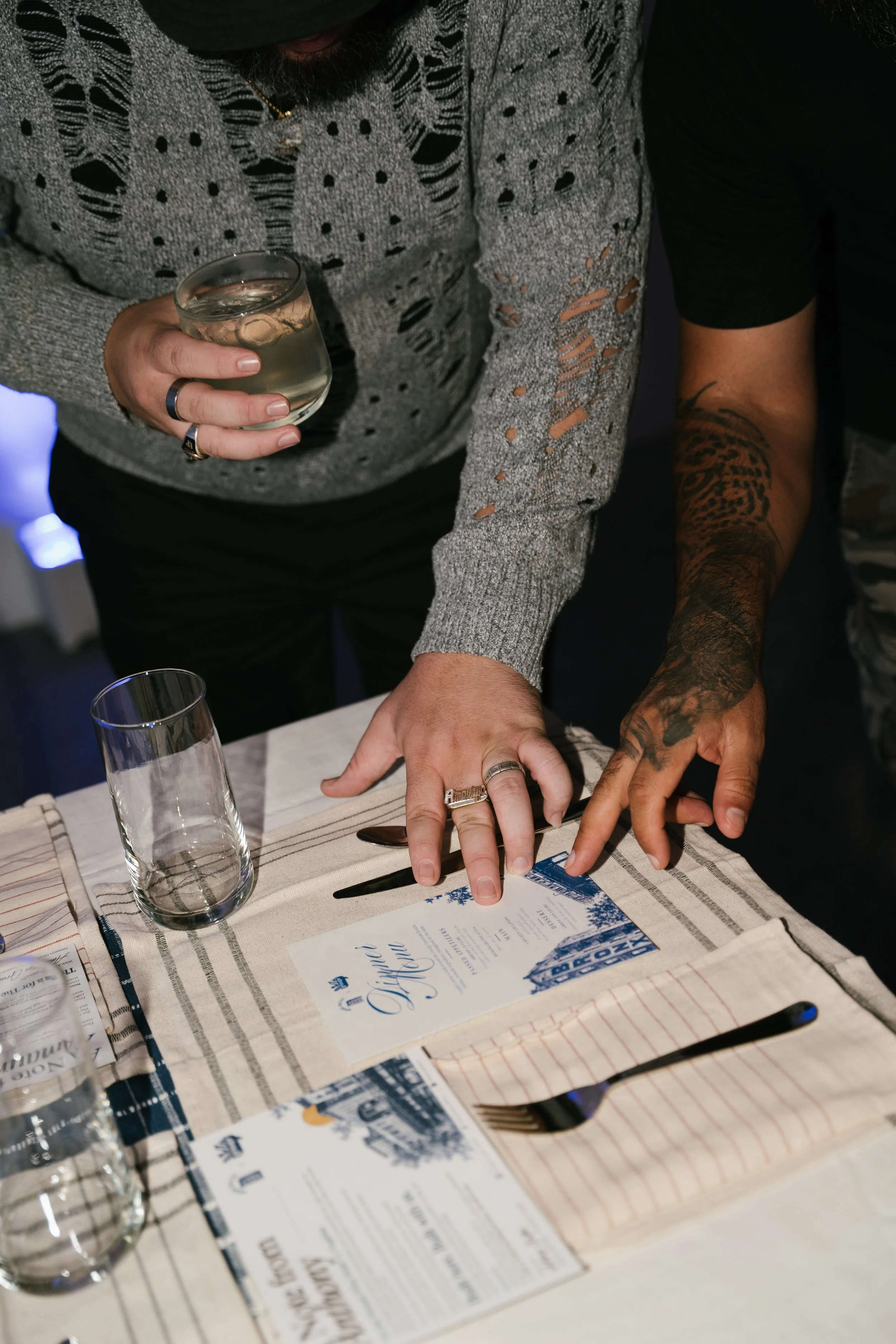 People at a table looking at a menu, with glasses of water, and pens, in a casual dining setting.