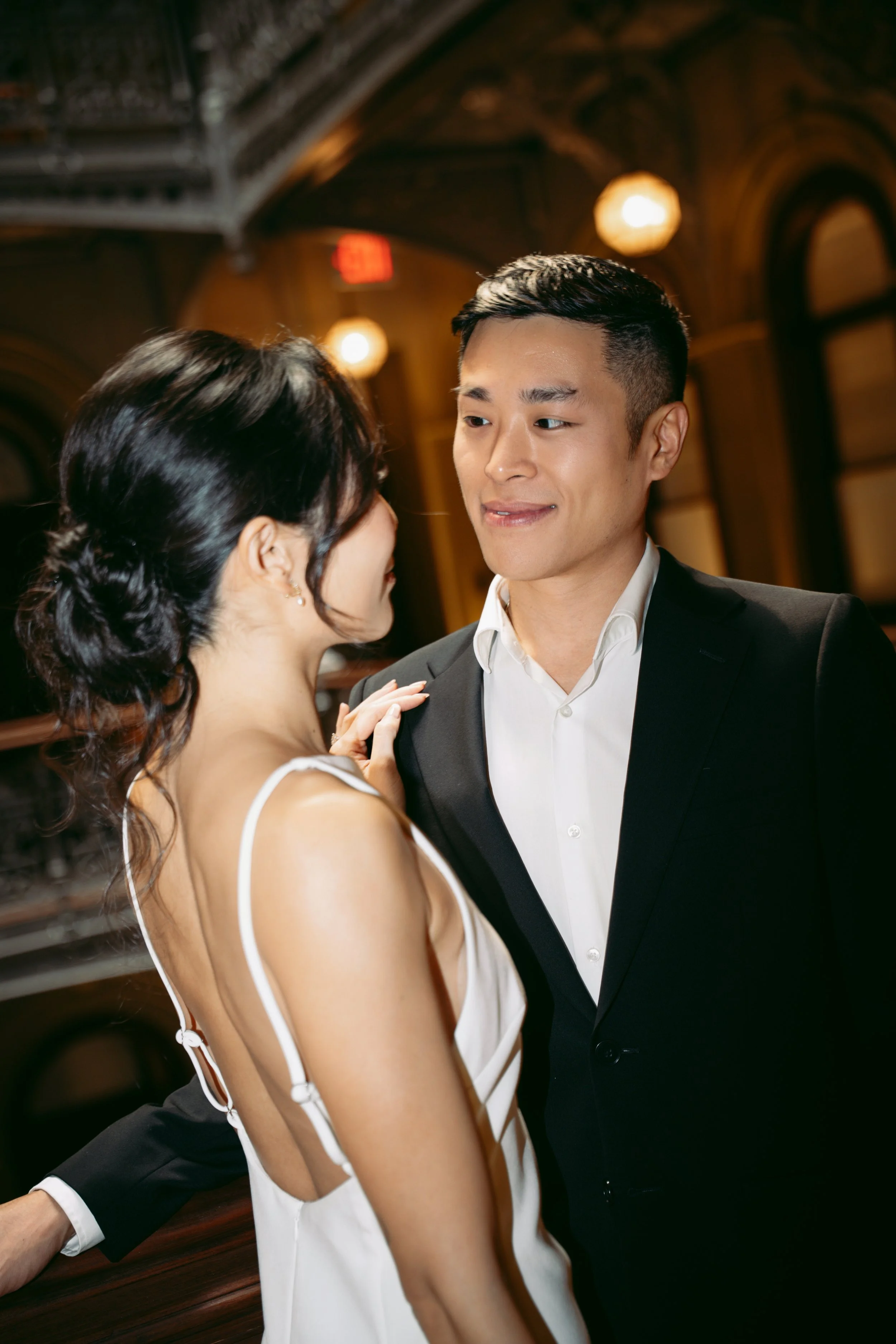 A couple dancing closely in an elegant indoor setting, with warm lighting and ornate architecture.